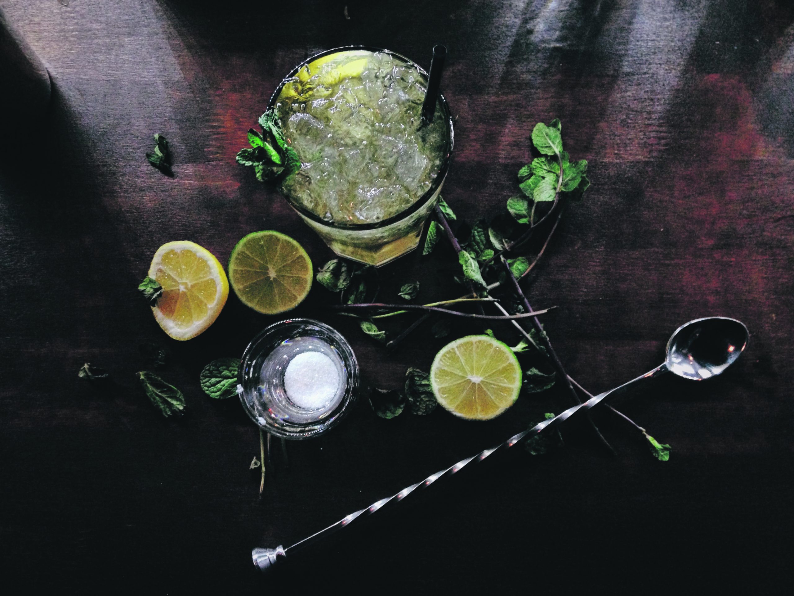 Making mojito cocktails with white rum, sugar, lime juice, soda water, and mint.