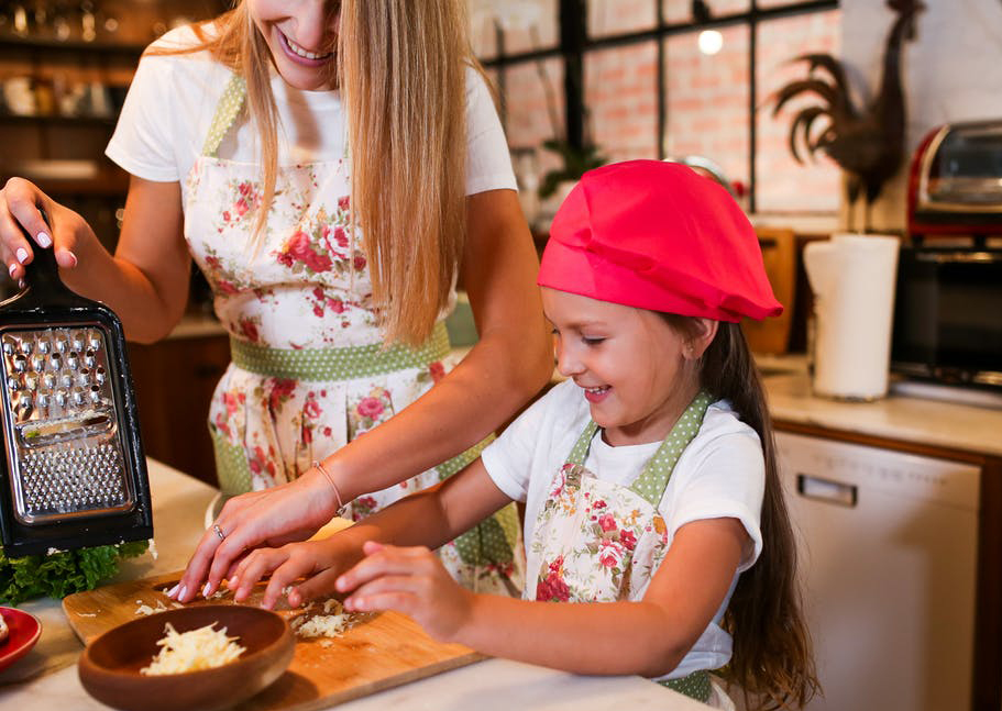 A kid learning to cook with her mother.