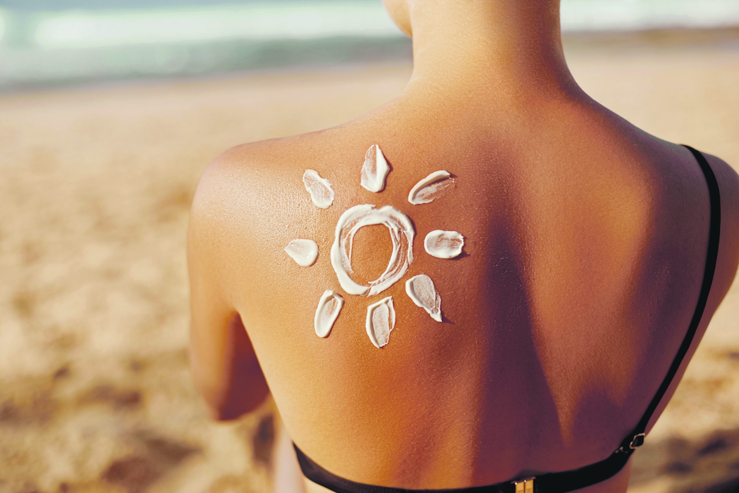 A woman with sun tan lotion on her back in the shape of the sun