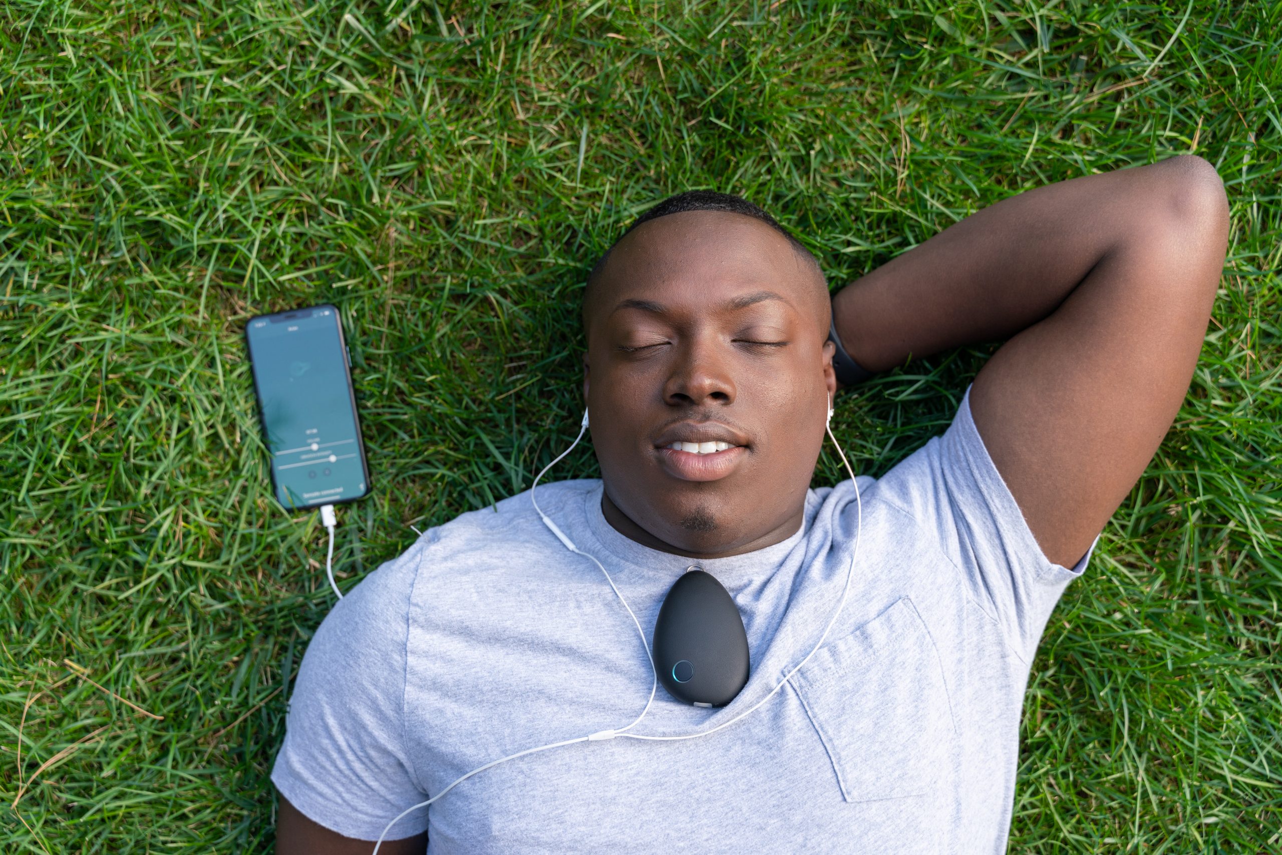 A man lying down with his eyes closed uses a Sensate sensory device on his chest to reduce anxiety