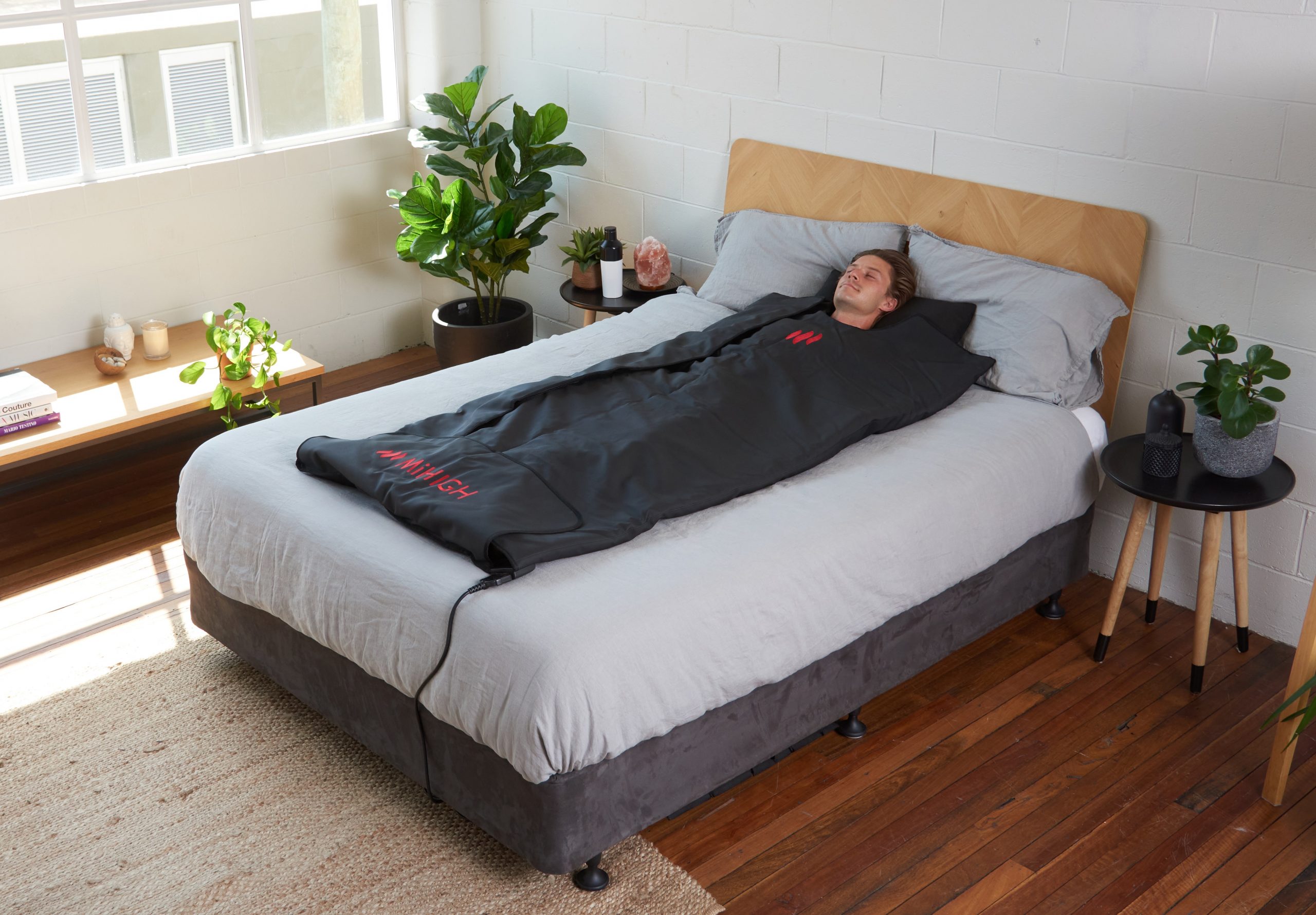 A man tries out the MiHigh at-home infrared sauna blanket on their bed