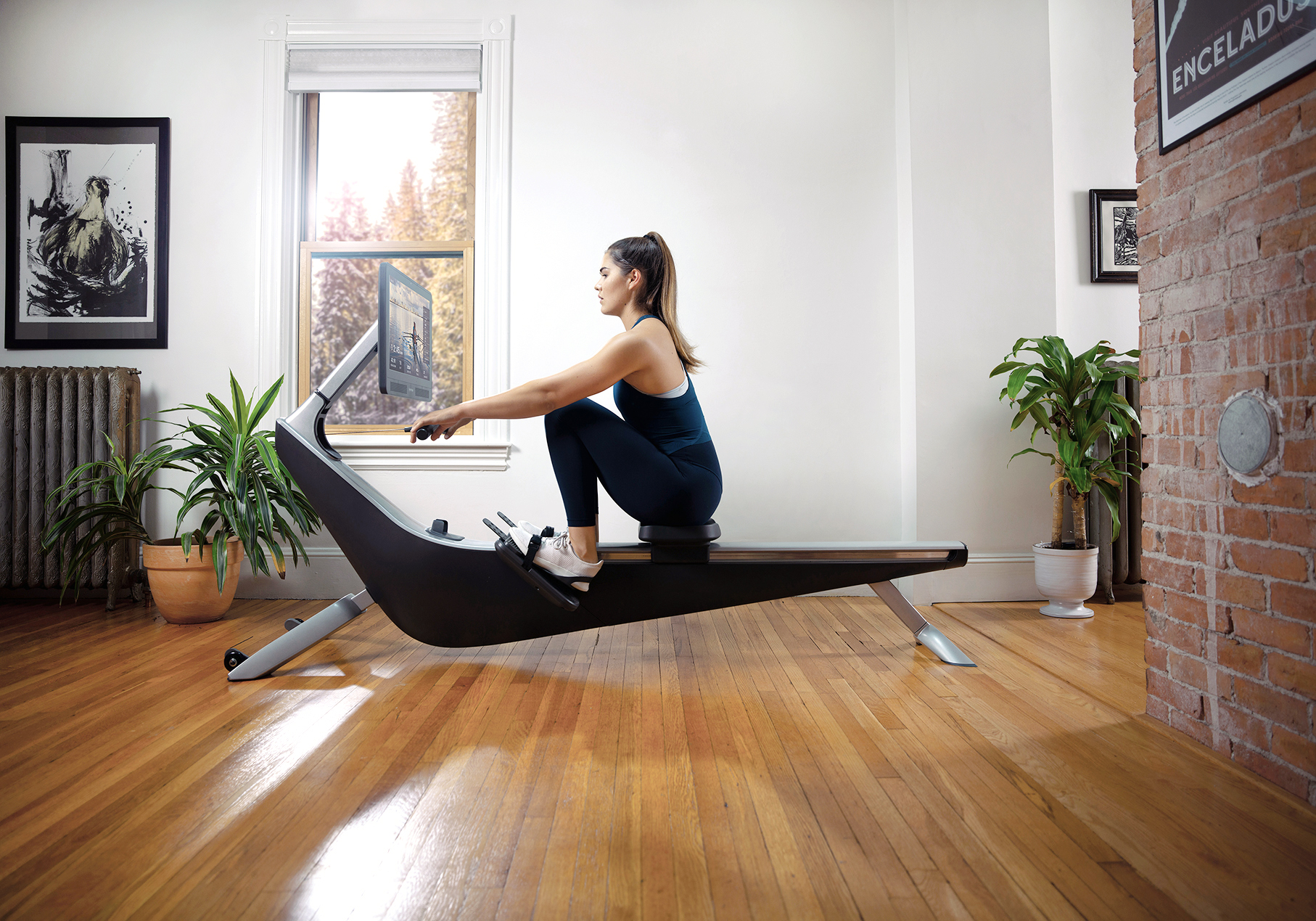 A woman trains on her Hydrow rowing machine at home