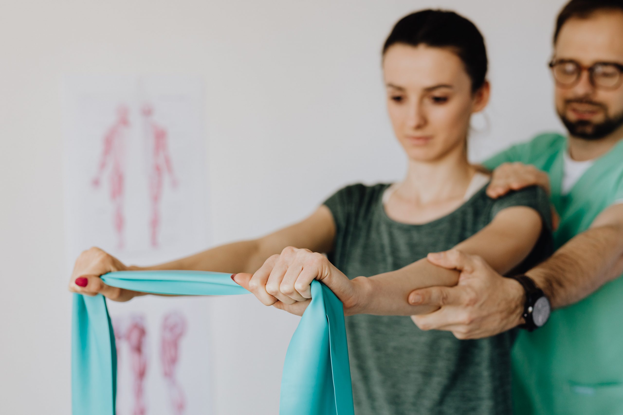 A woman exercising with resistance bands gets helps from her trainer