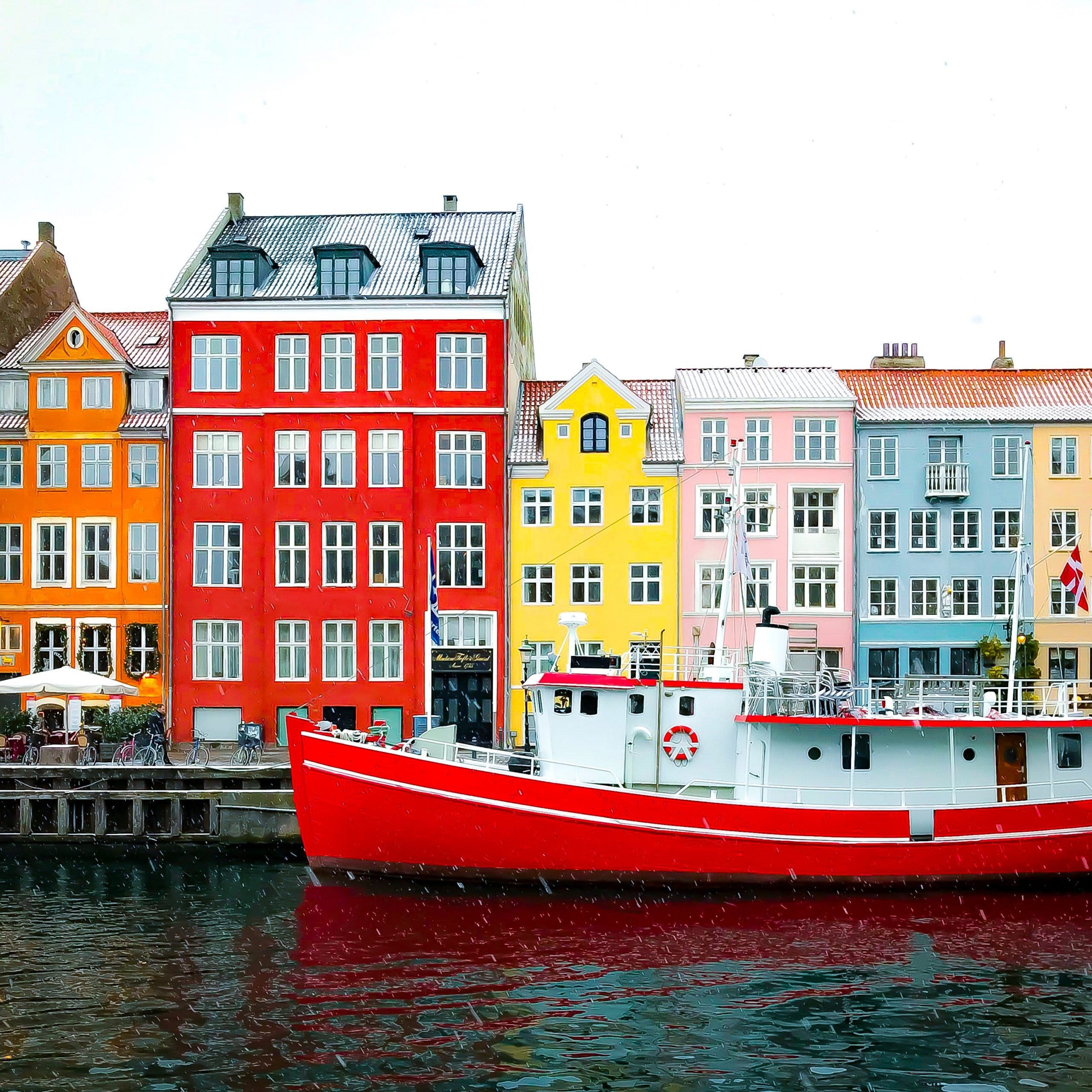 A red boat passing a red building in Copenhagen, Denmark.