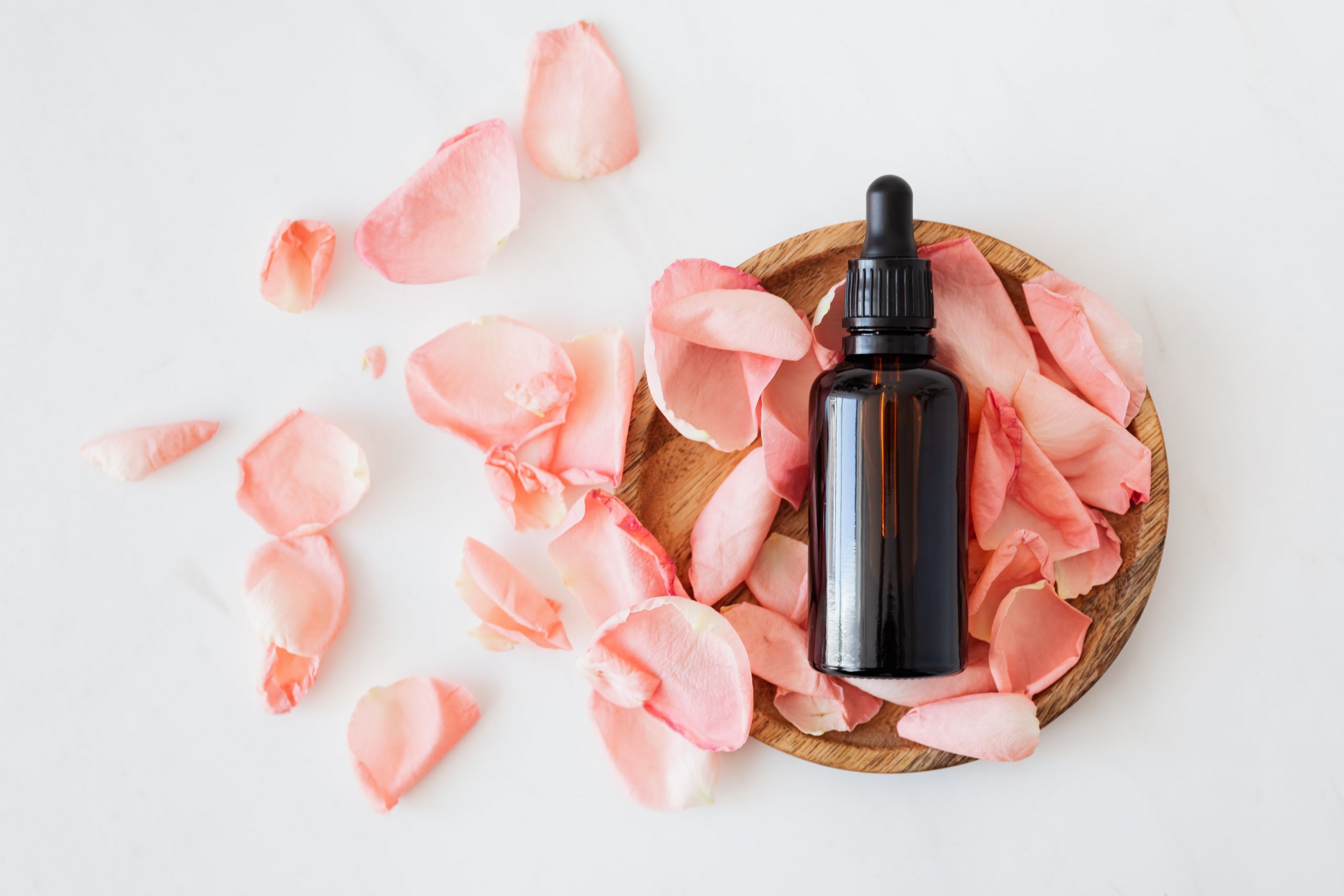 A bottle of organic cosmetics surrounded by rose petals