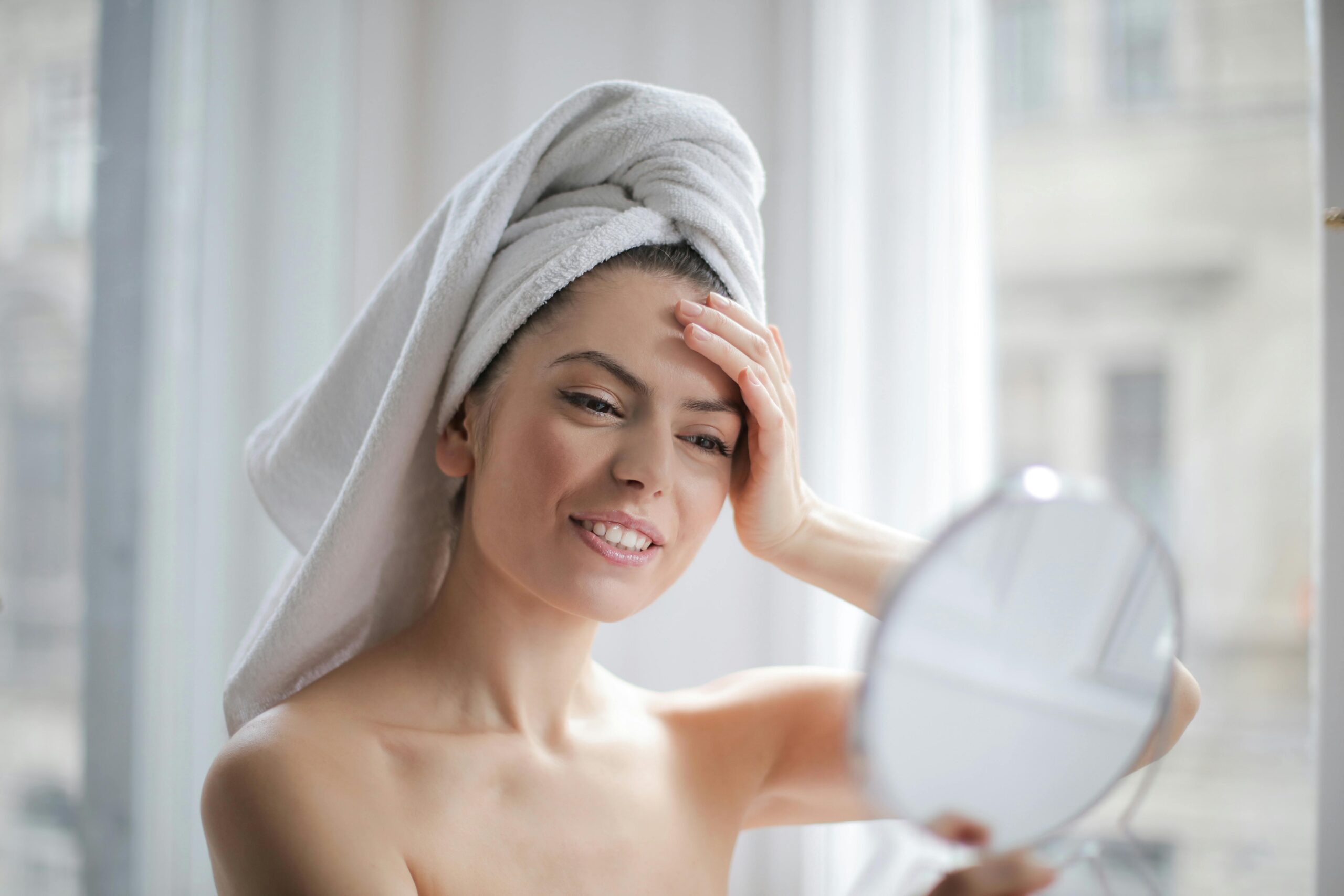 Woman smiles in the mirror as she checks her skin