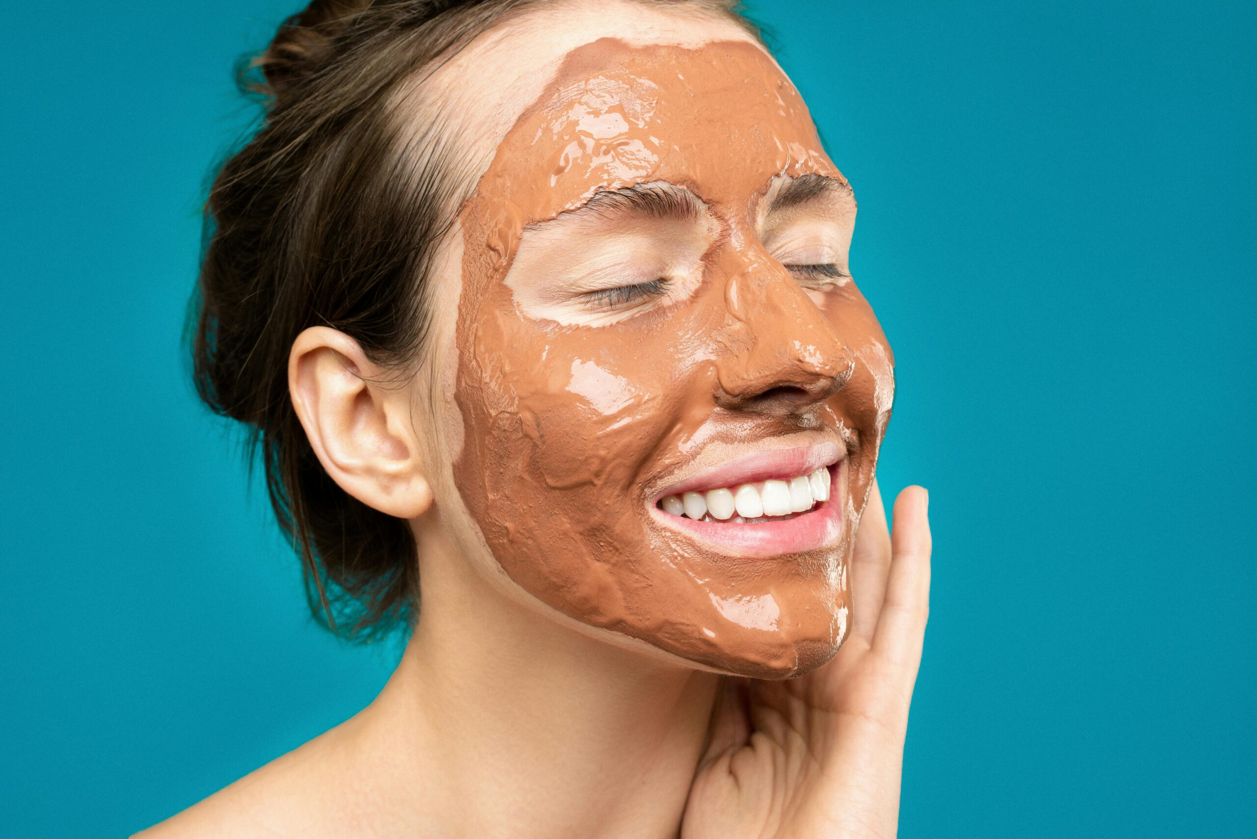 Woman smiles as she wears a mud face mask