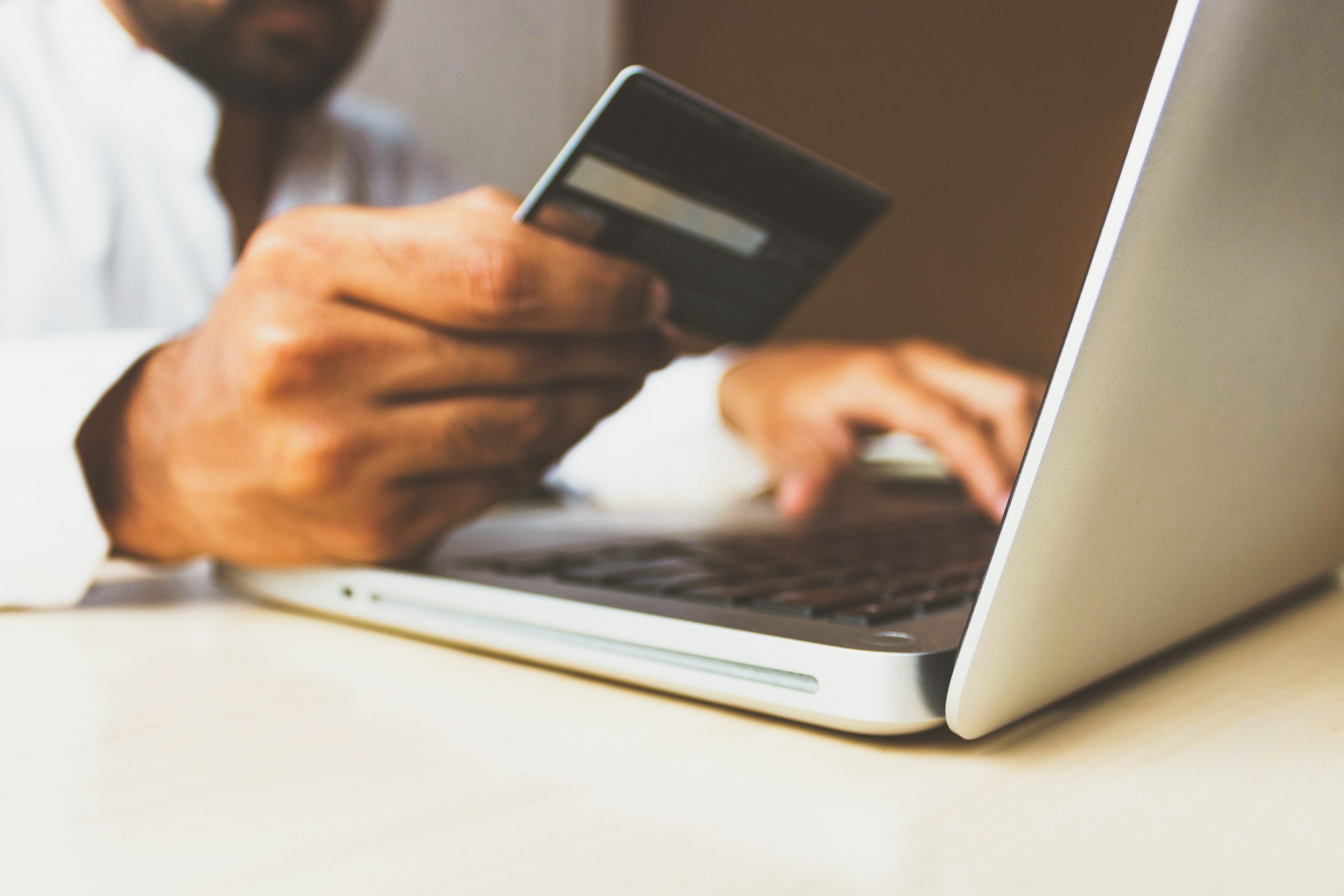 A man inputs his credit card details online on a laptop