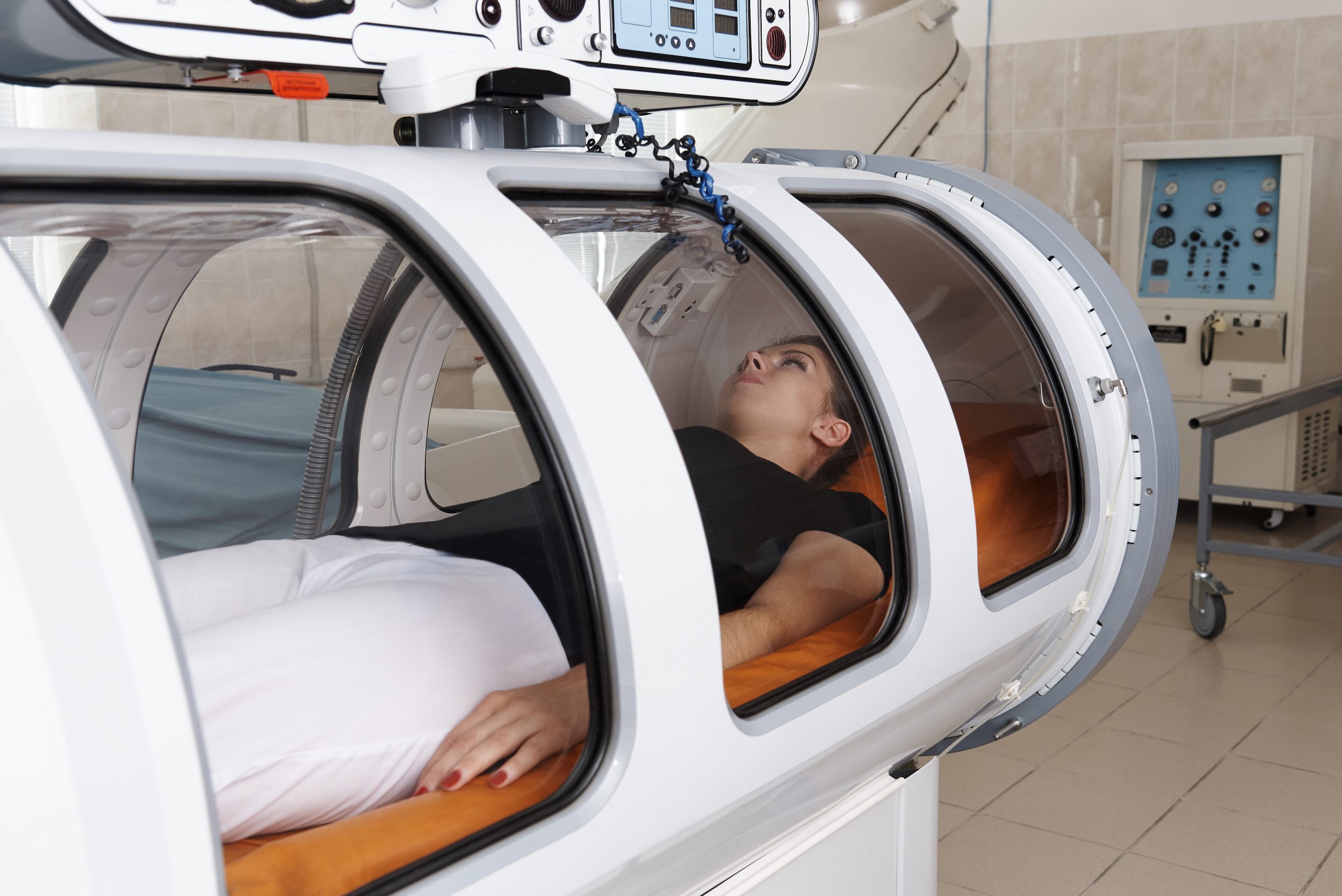 Lying outstretched inside a chamber, a woman receives hyperbaric oxygen therapy