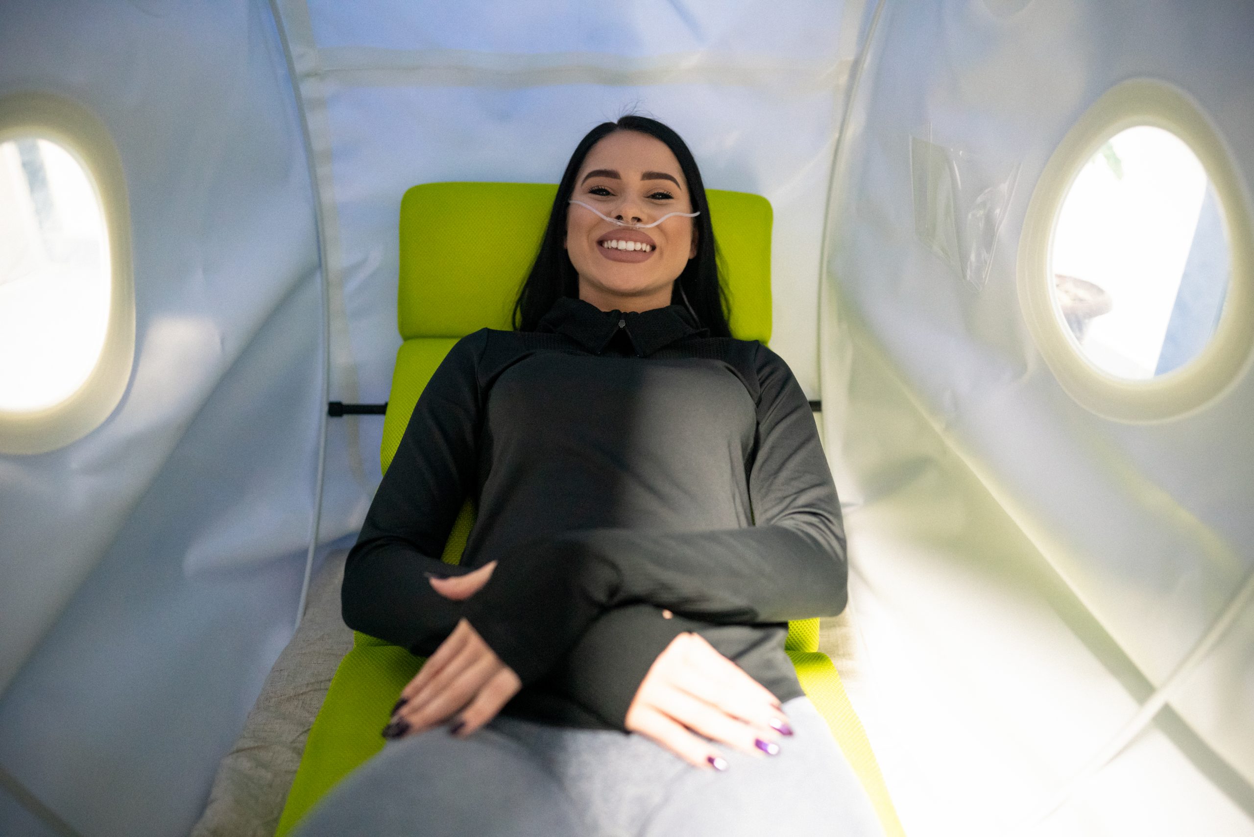 A woman lies comfortably inside a hyperbaric oxygen therapy chamber