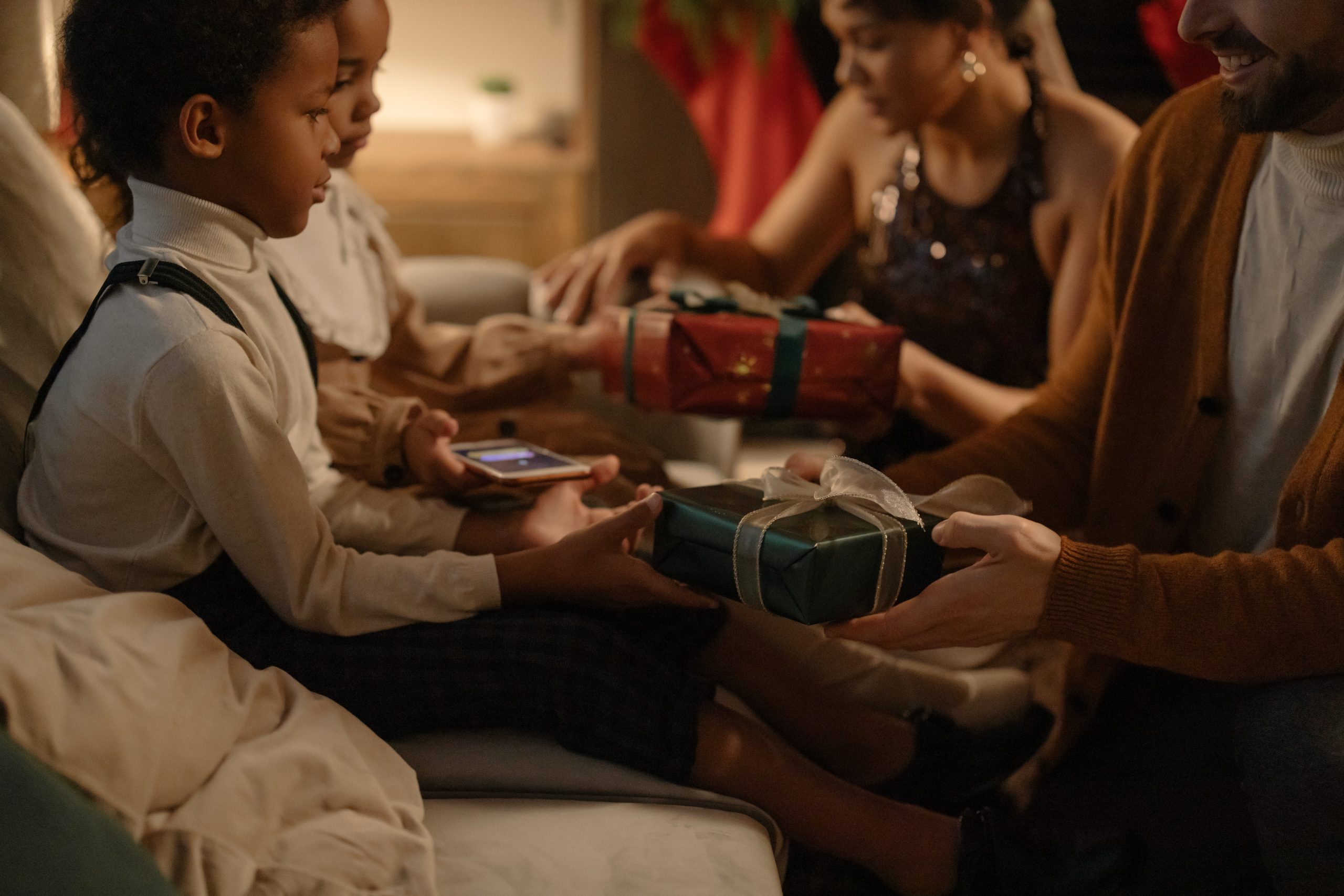 A father and mother exchanges Christmas gifts with their young children