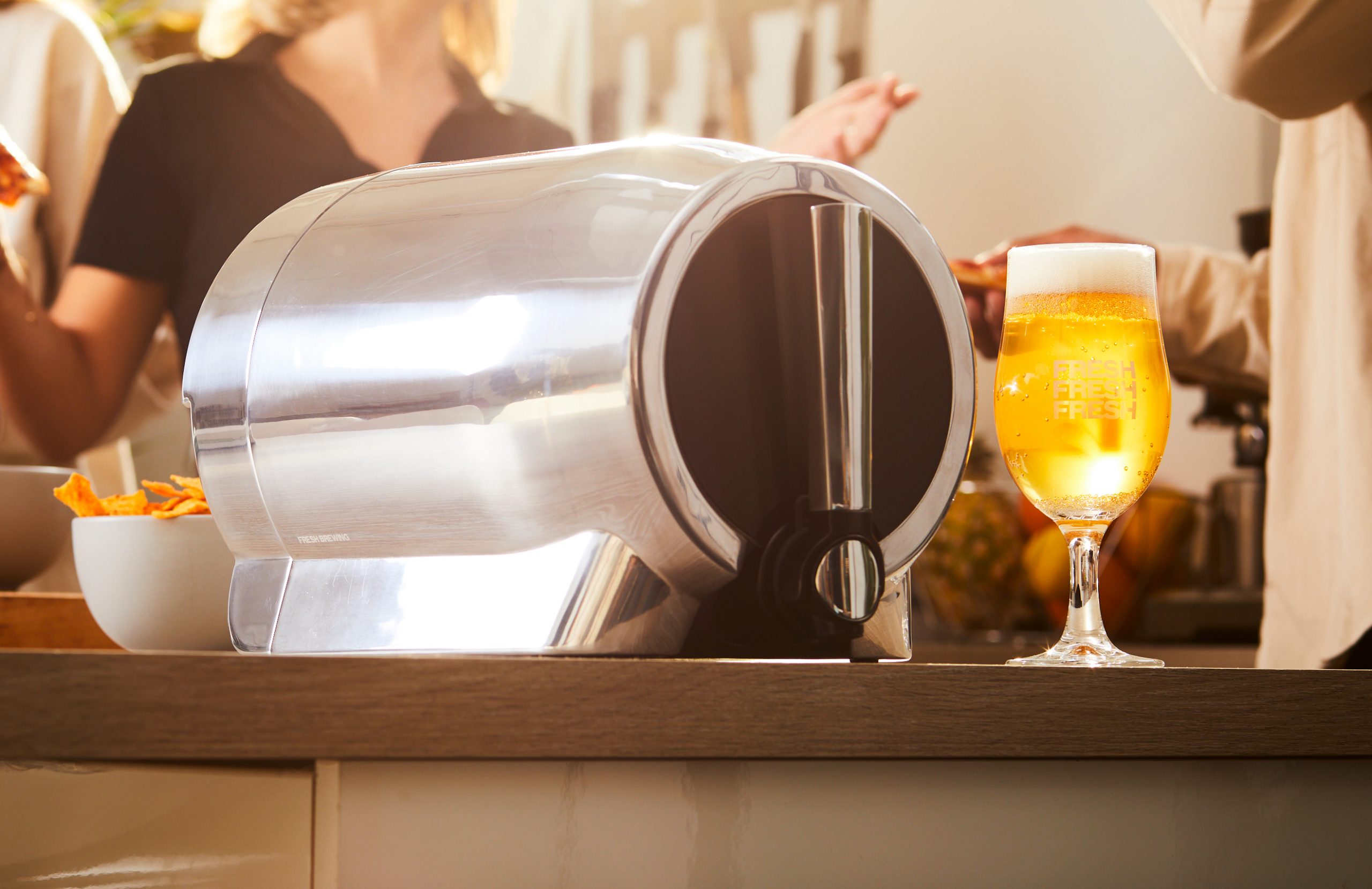 At-home brewery gadget, The Pinter 2, showcased on a bar next to a glass of beer