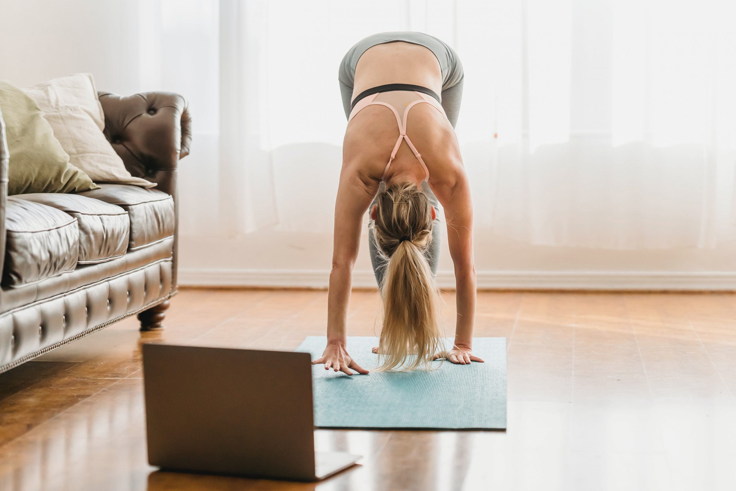 A young woman attends an online yoga class from the comfort of her own home.