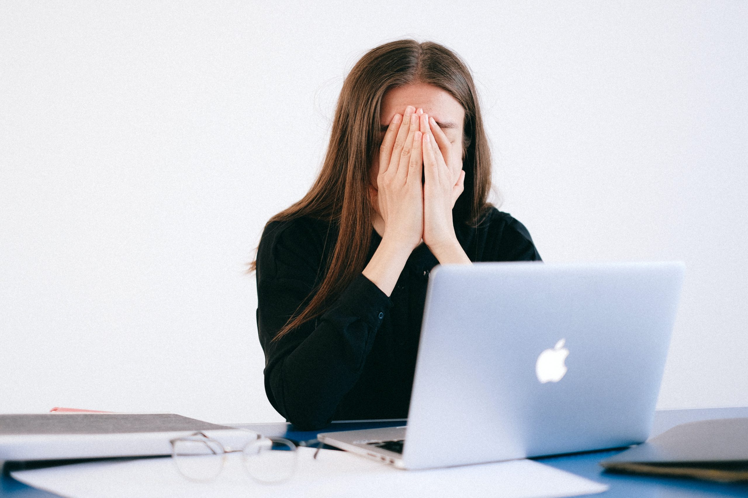 A woman working on her laptop focuses on breathing to reduce stress.