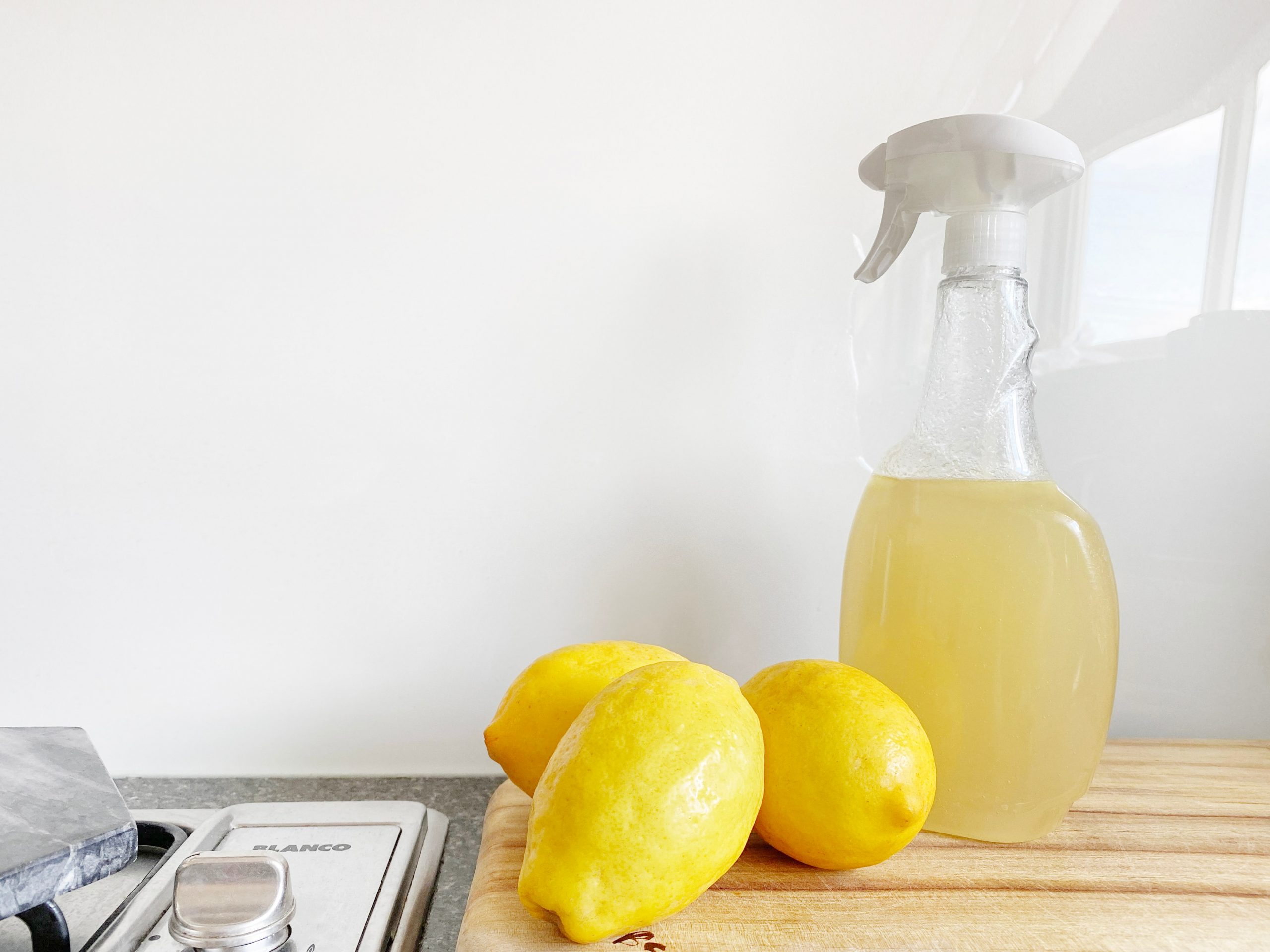 Three lemons next to a kitchen spray made with castile soap.