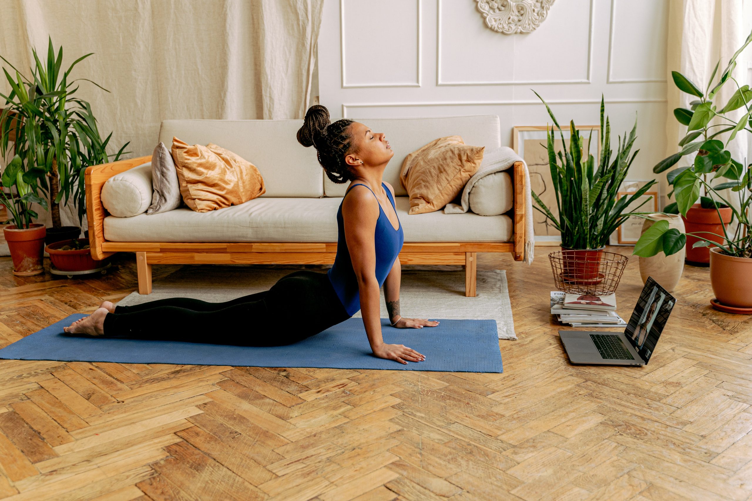 A young woman practises yoga from her living room to reduce the symptoms of PMS.