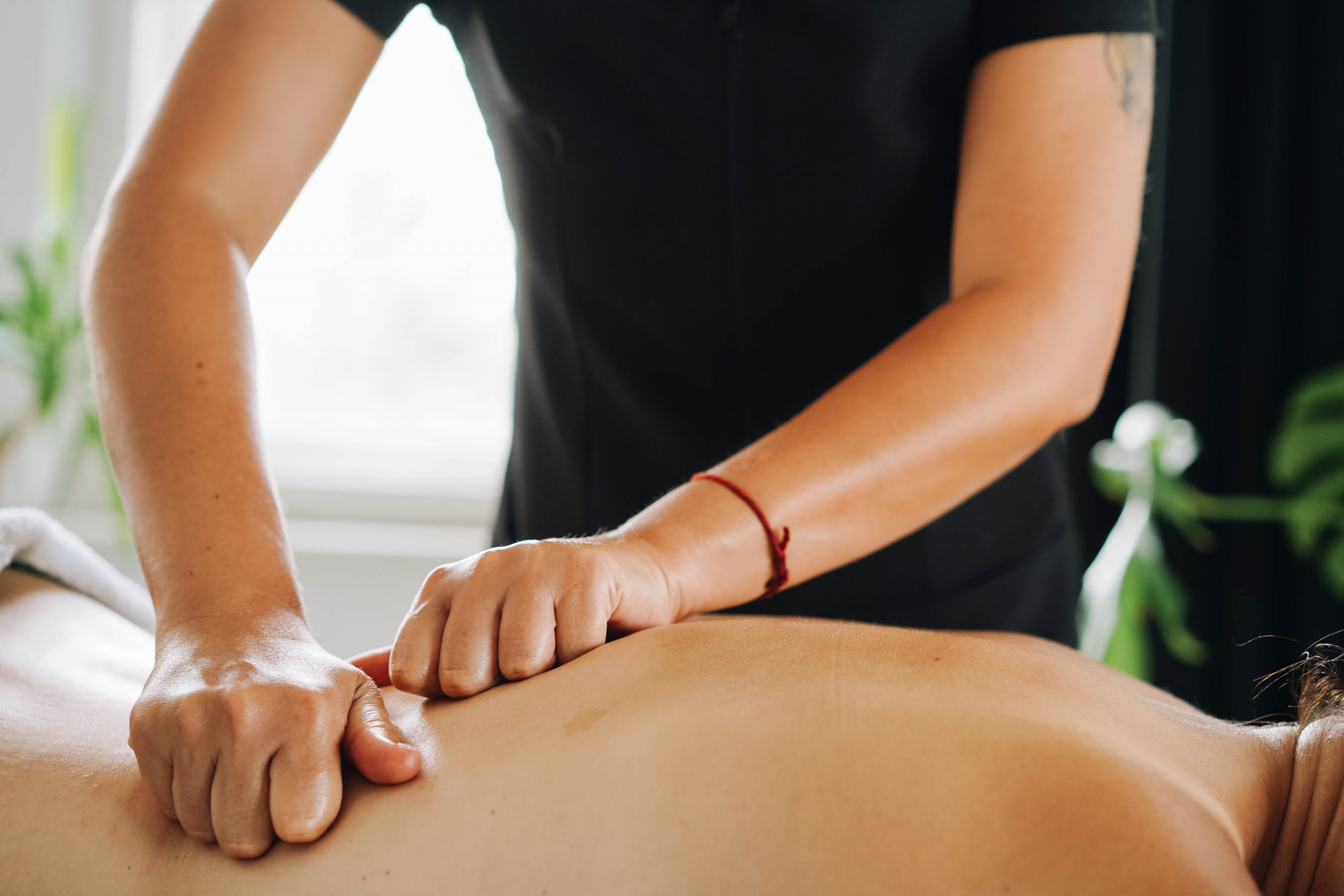 A patient receives a massage on her back from a therapist.