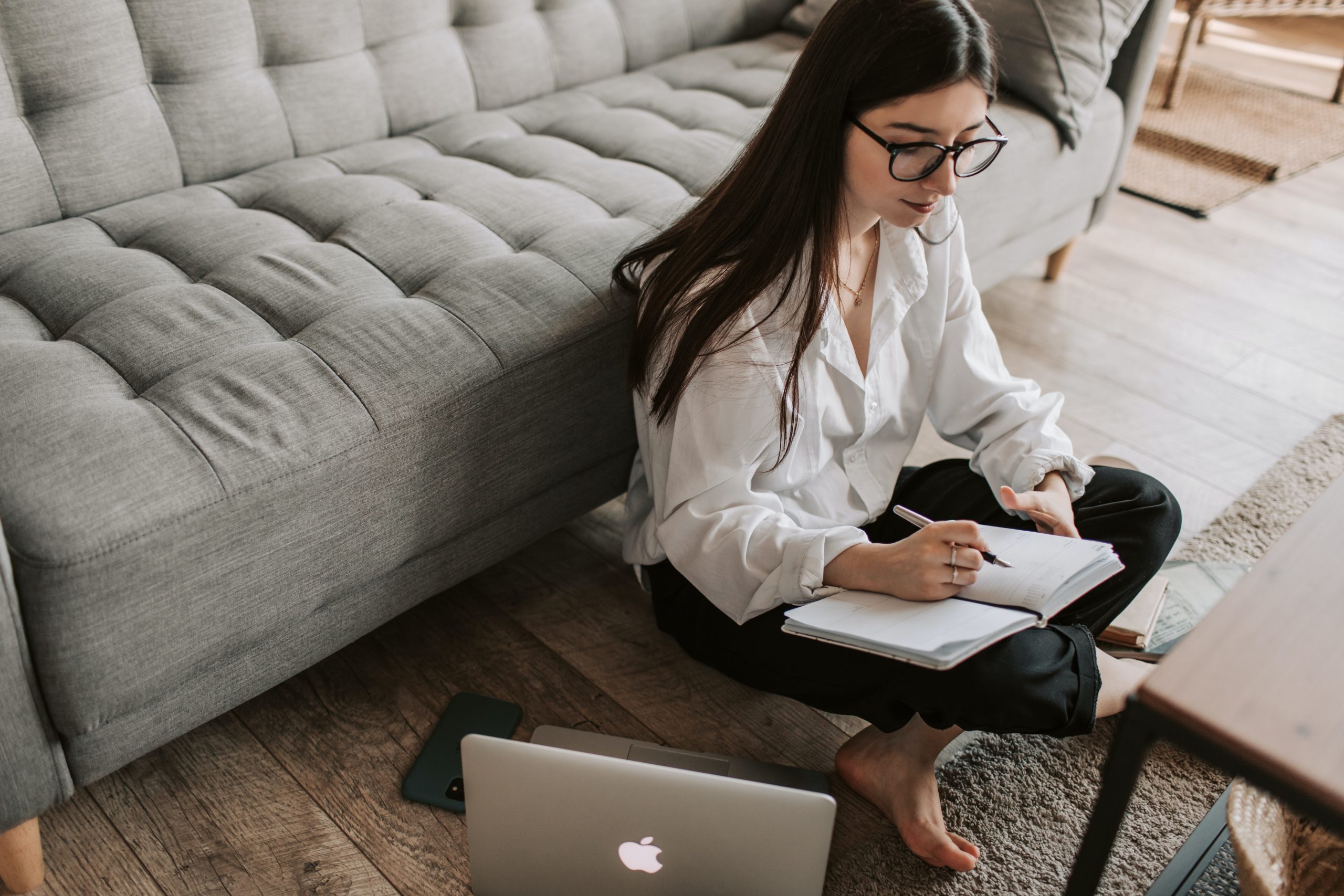 A young woman composing her complaint in a notebook before emailing it. 