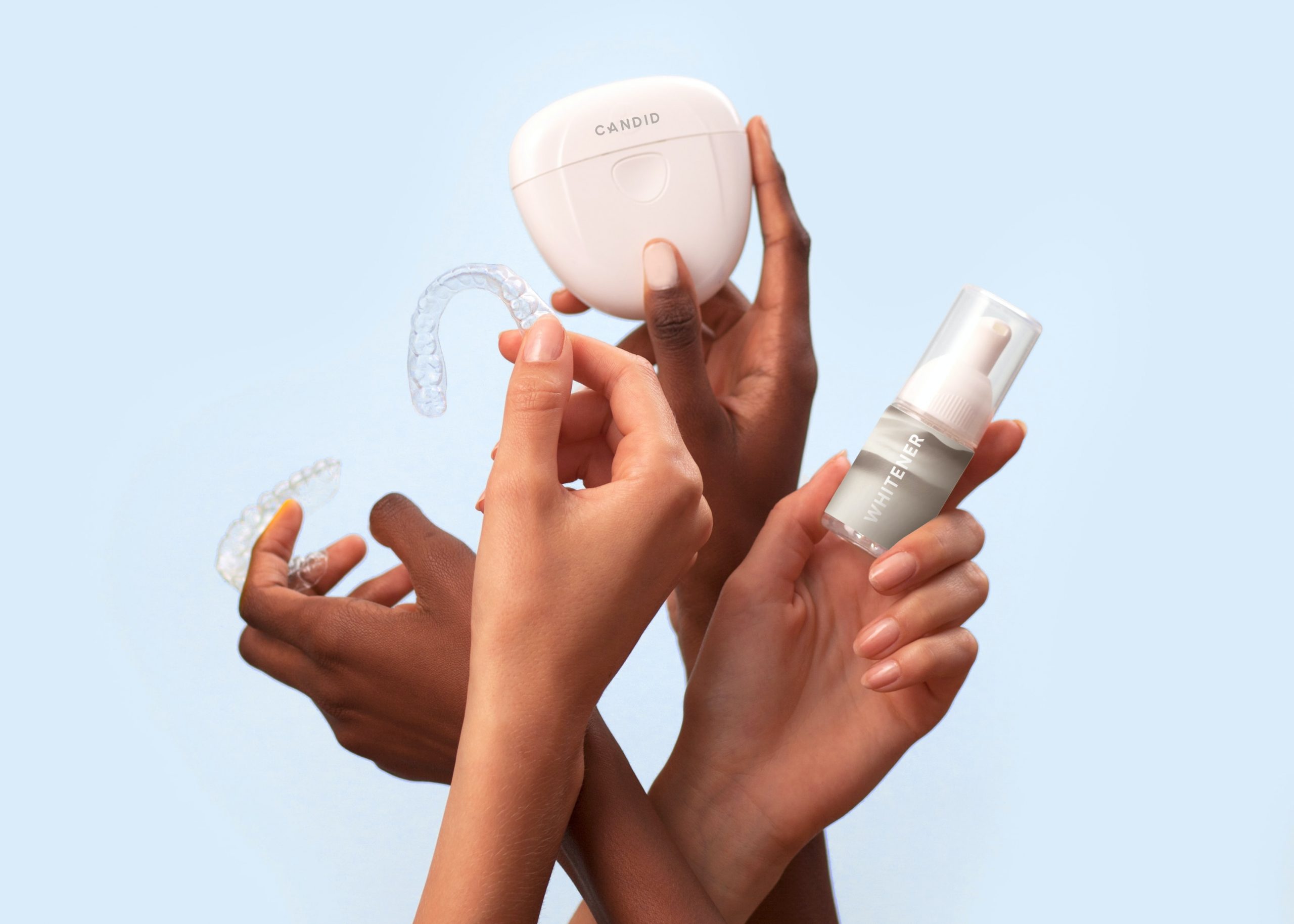 Four hands holding up a selection of cosmetic treatments including nightguards.