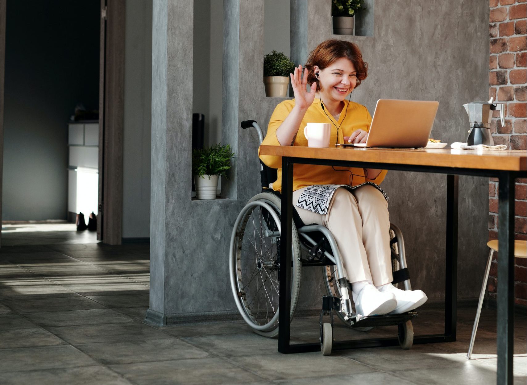 A young woman in a wheelchair works remotely from her home.