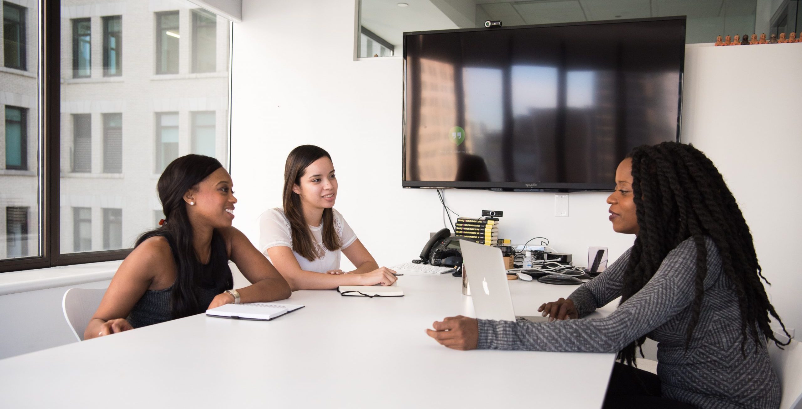 Three young women of different backgrounds in a business meeting.