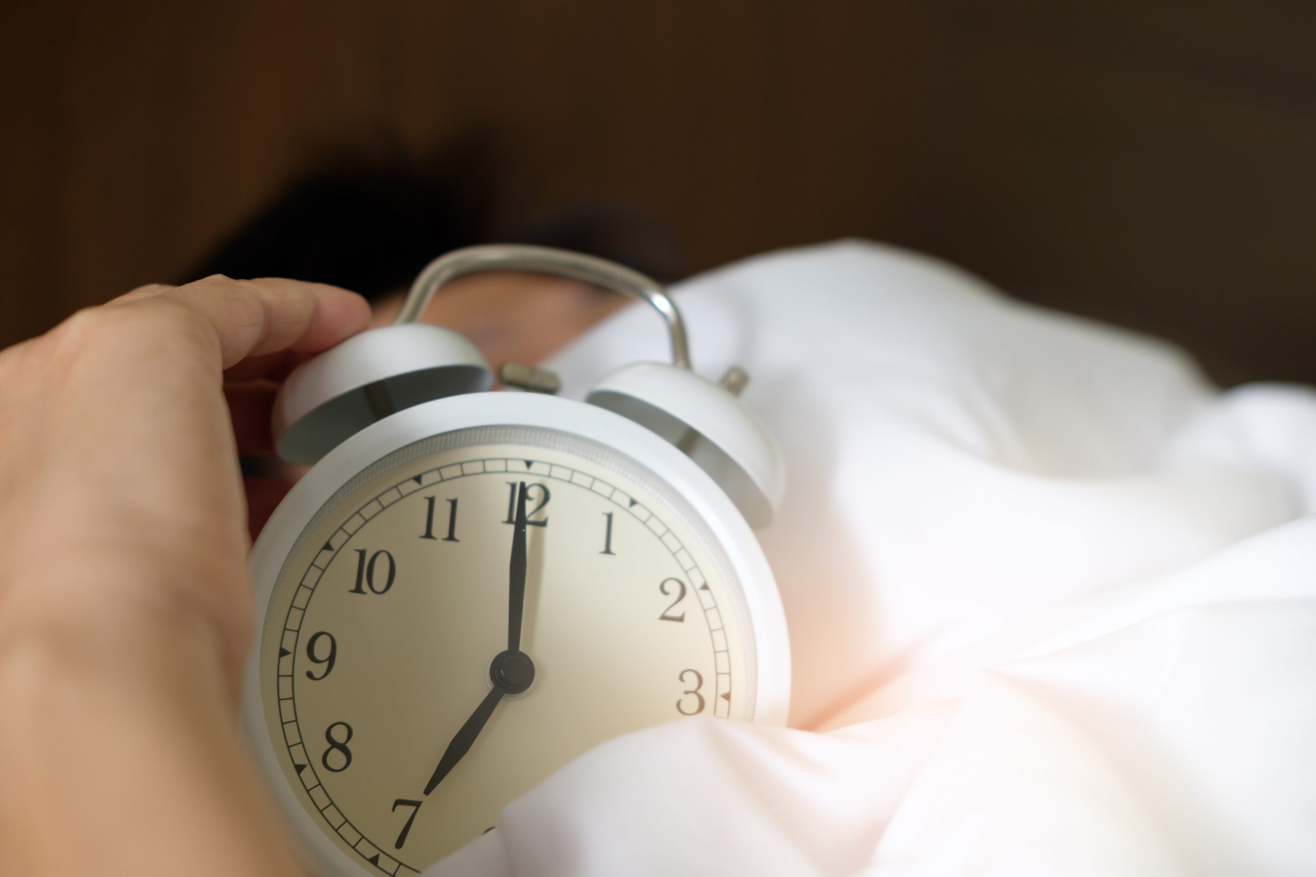 A man wakes up to the sound of his alarm clock ringing.