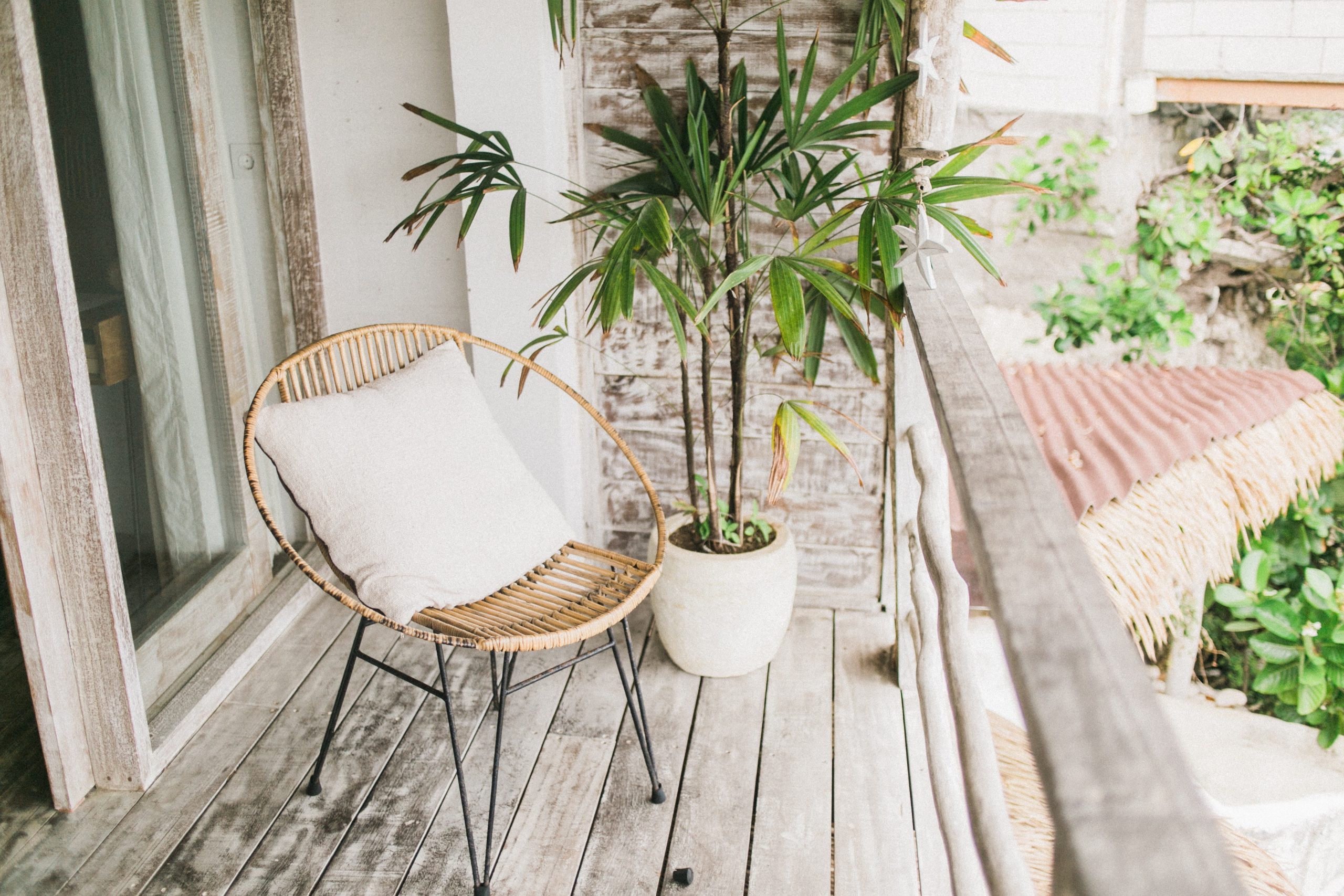 A single garden chair next to a potted plant on a wooden balcony.