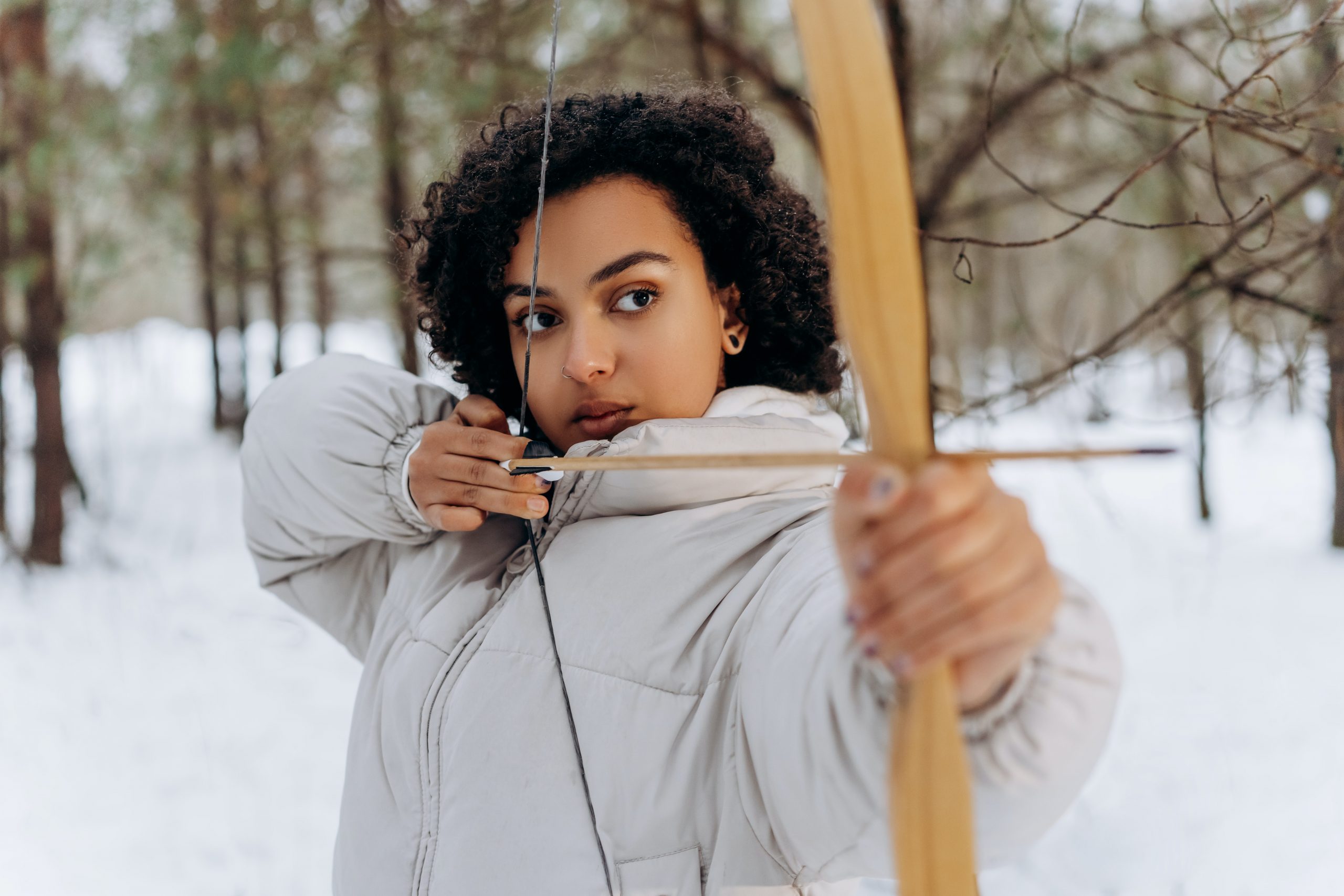 A young black woman tries her hand at the one-hour archery experience.