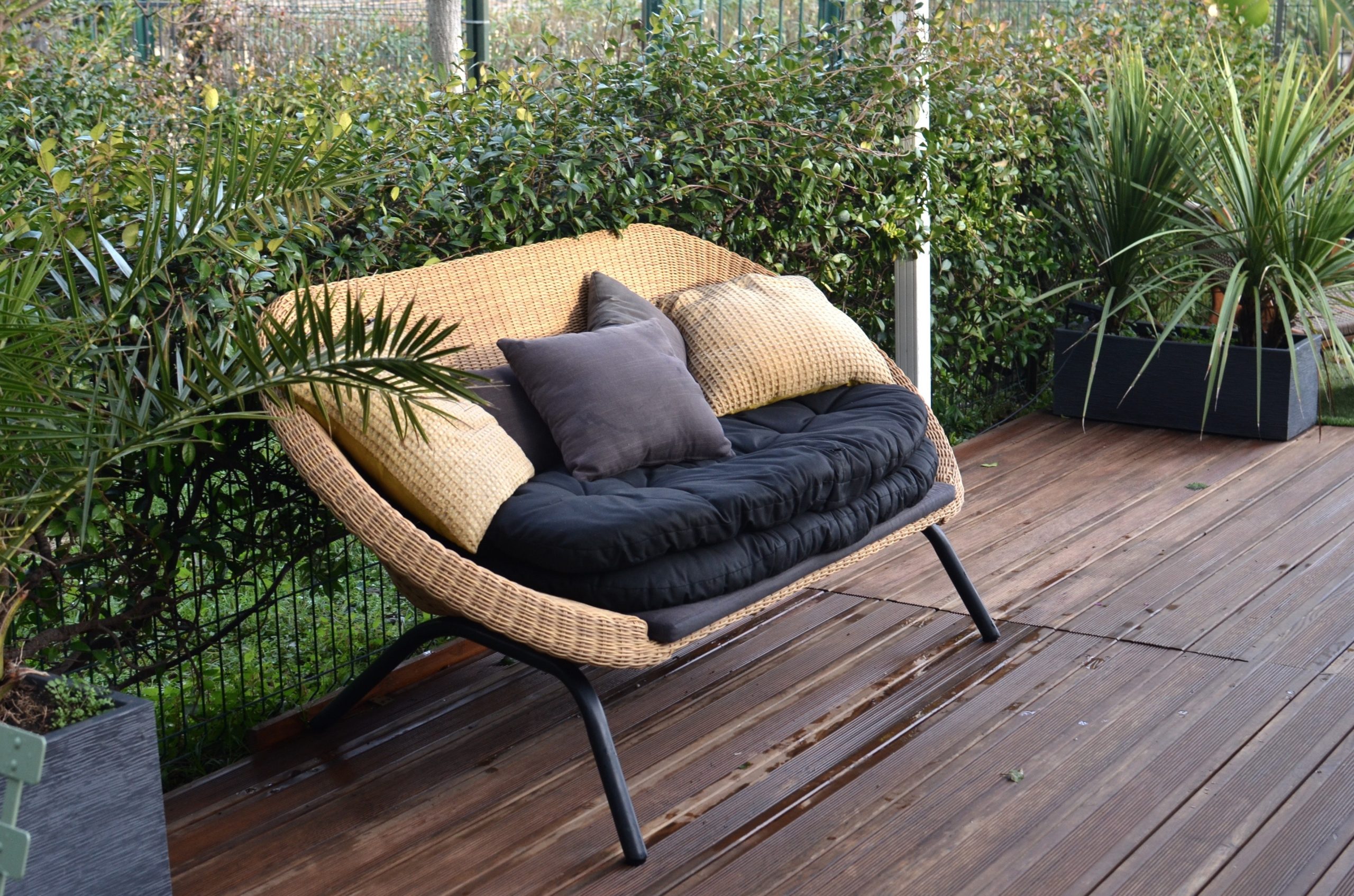 A garden sofa on a patio made of dark oak decking.