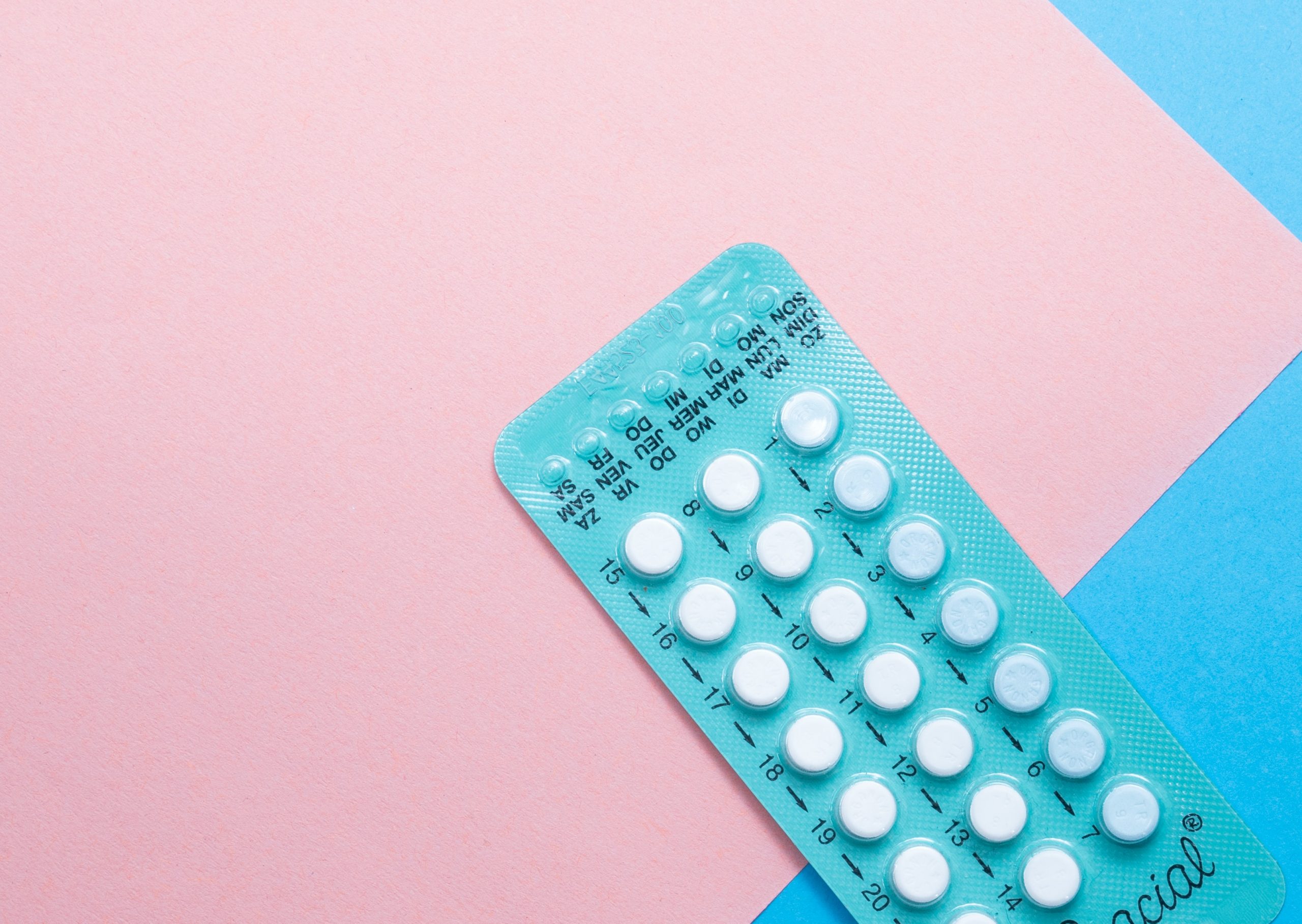 Contraceptive pills against a pink and blue background.