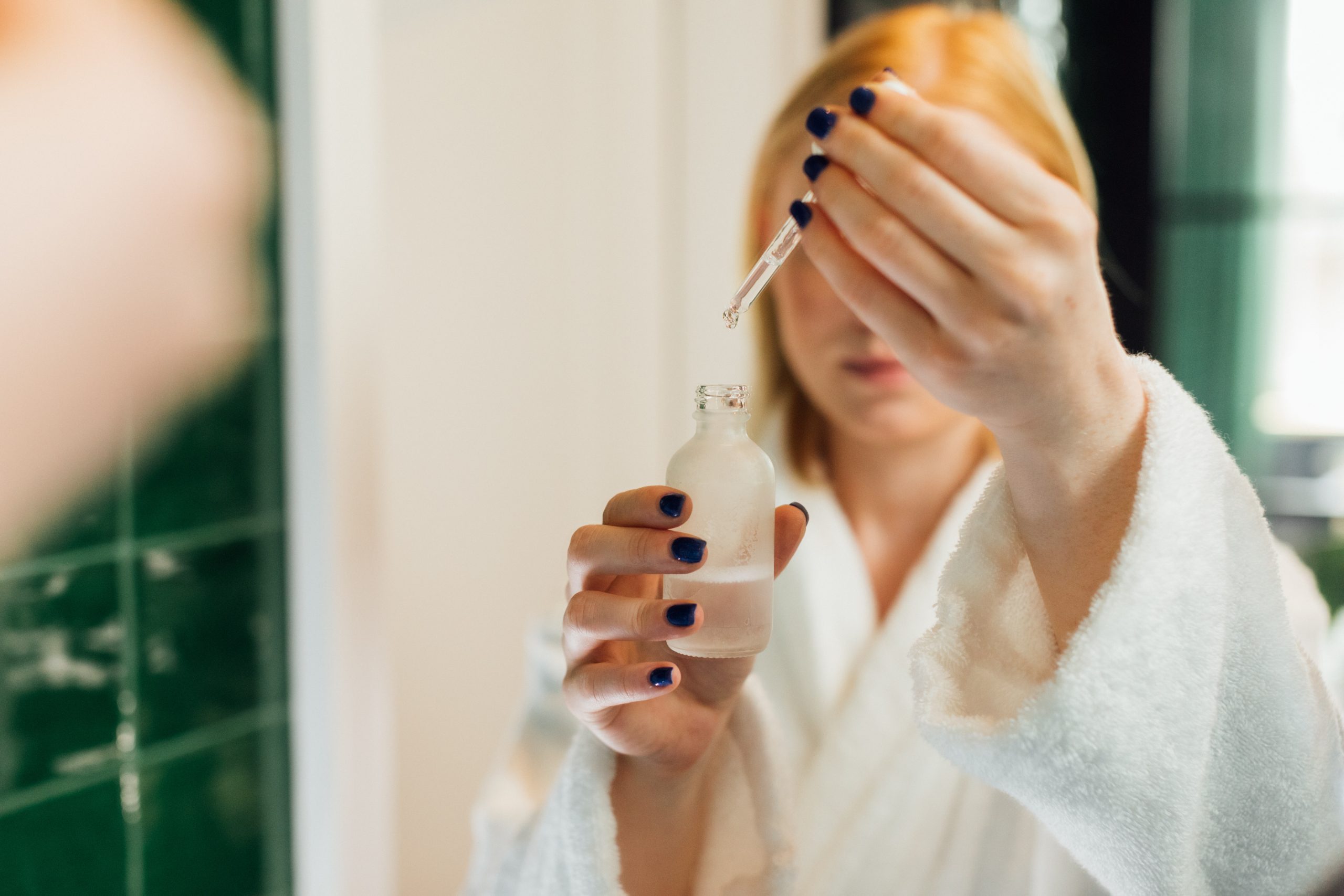 In a bathrobe, a young woman prepares to use essential oils in her bath.