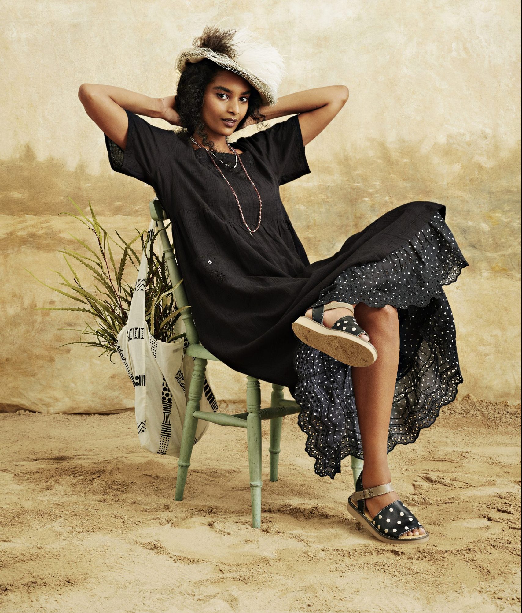 A beautiful black woman models a Gudrun Sjödén black dress and white hat.