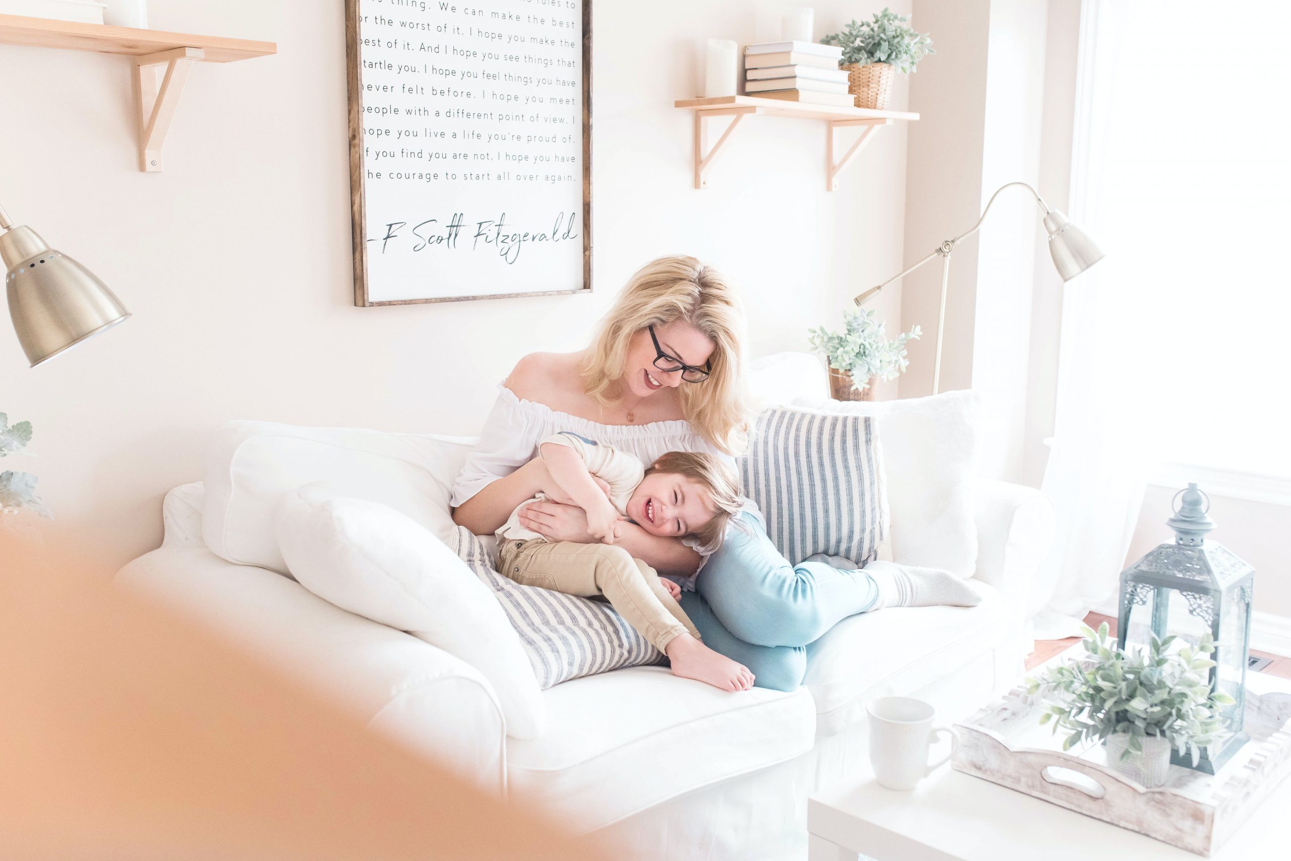 On their living room sofa, a mother and teen son cuddle each other, laughing.