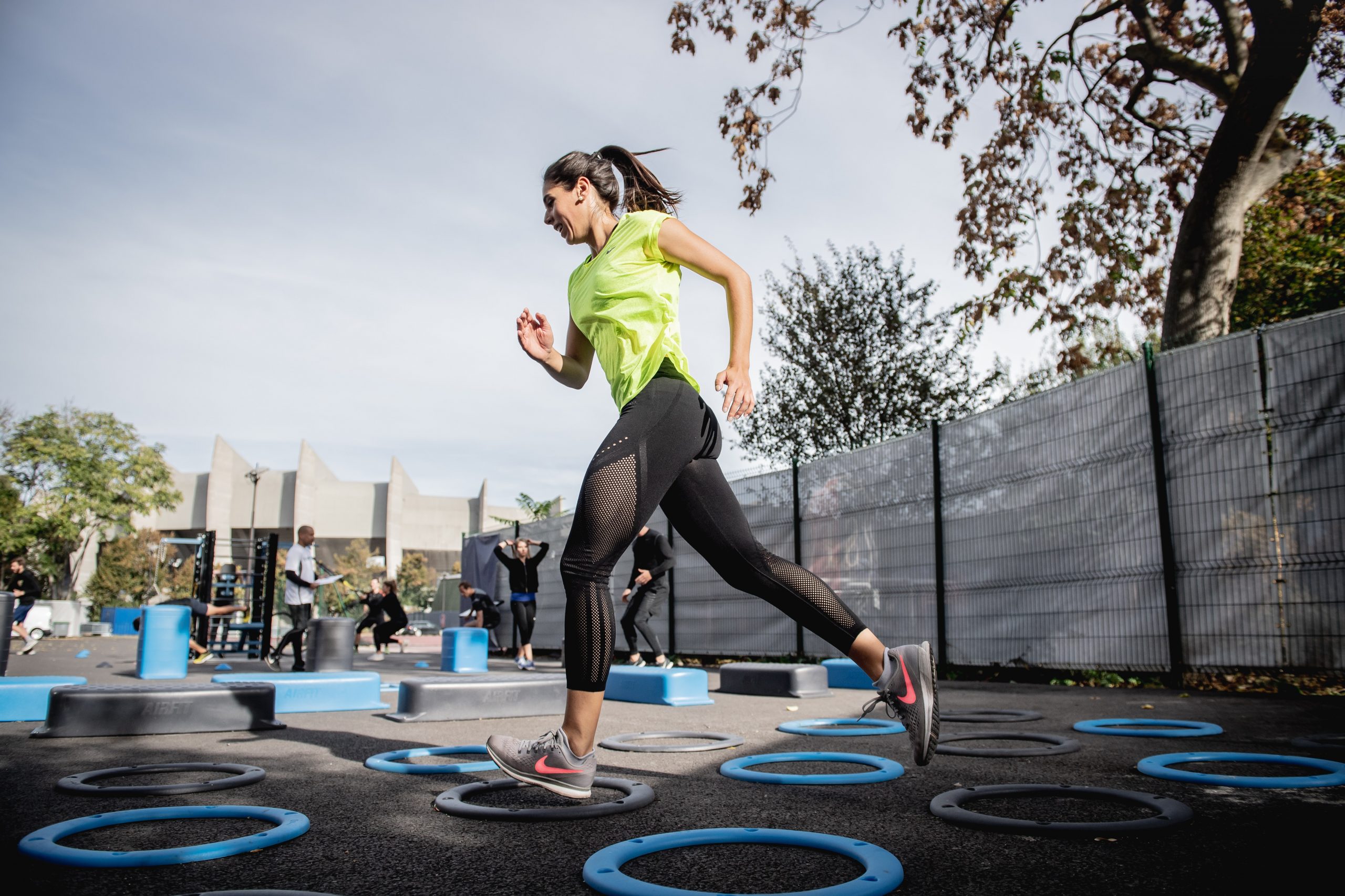 A young woman agility training with blue hoops on the ground in the city.