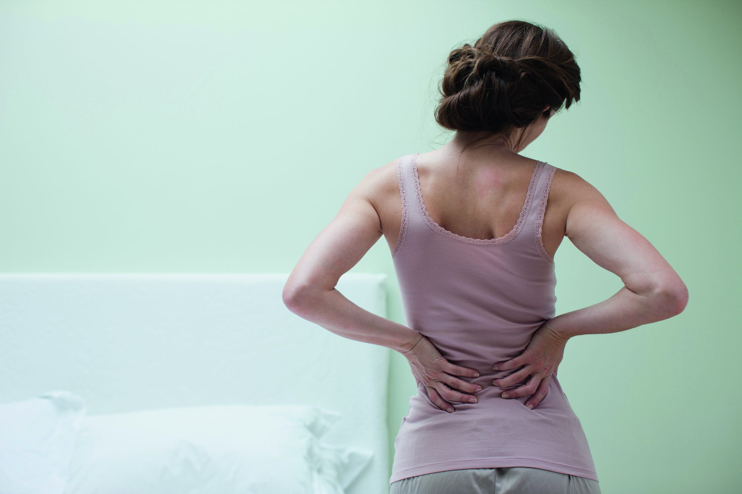 A woman rubbing her aching back in the morning.