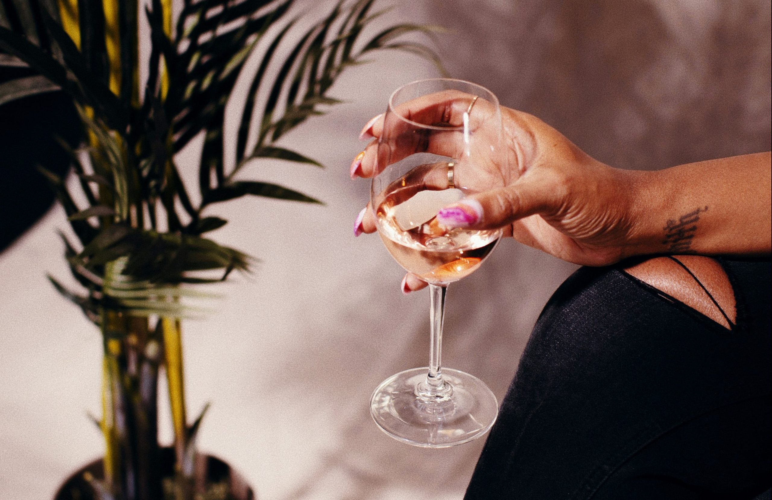 Close-up of a woman's hand holding a glass of amie x rosé.