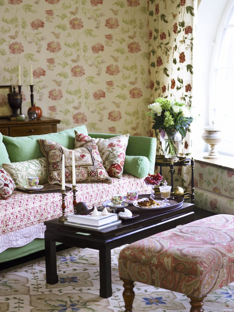 A living room decorated with chintz: patterned sofas, cushions, carpet, curtains and wallpaper.