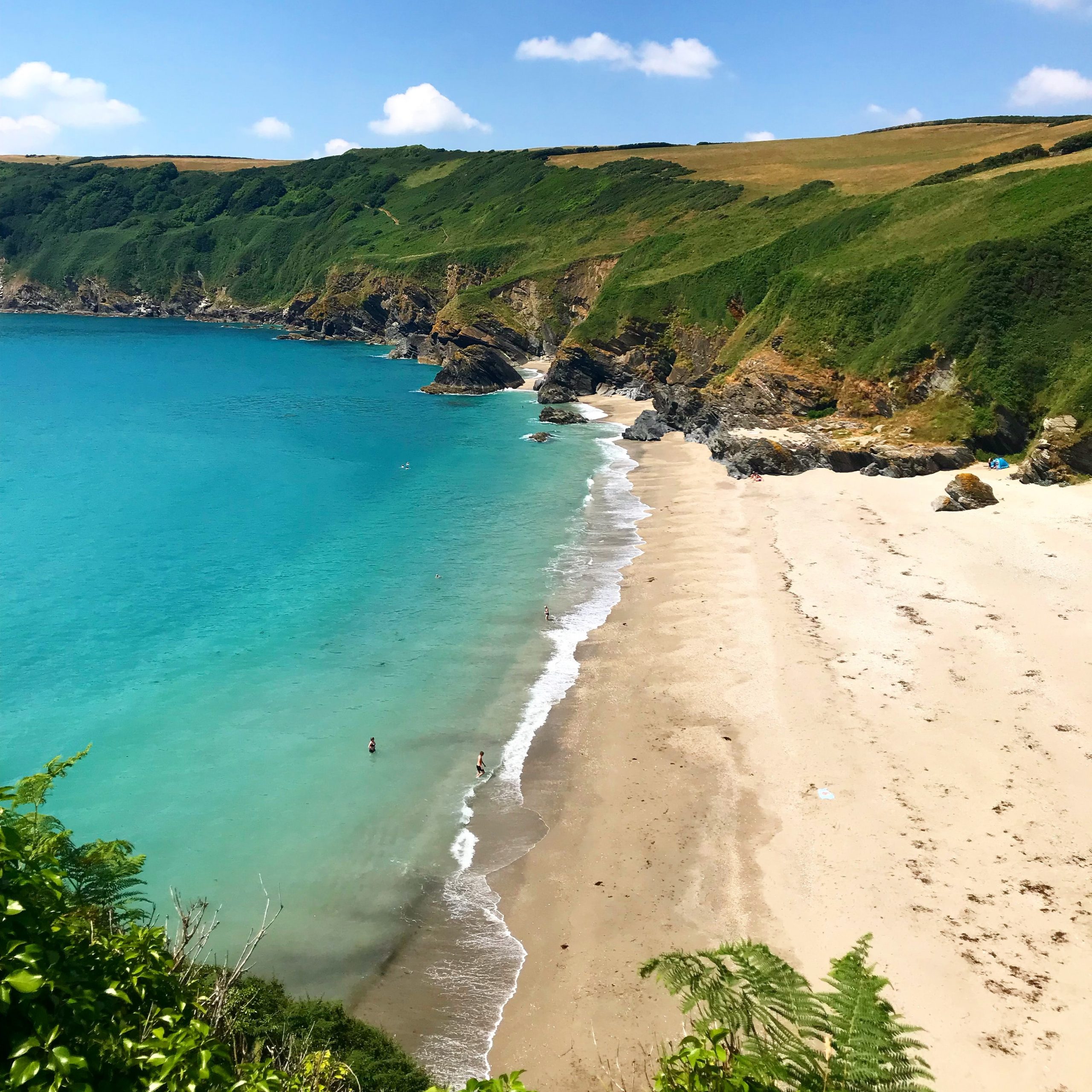 Aerial view of Lantic Bay, Cornwall, on a sunny day.