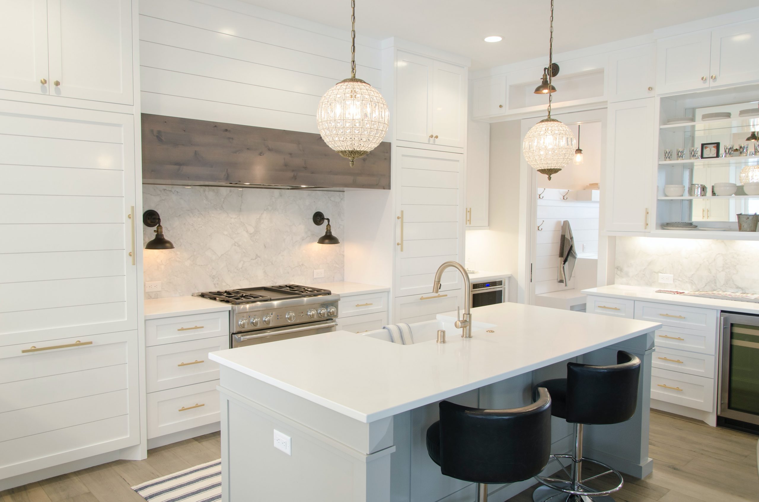 A modern kitchen designed all in white with black breakfast bar stools.