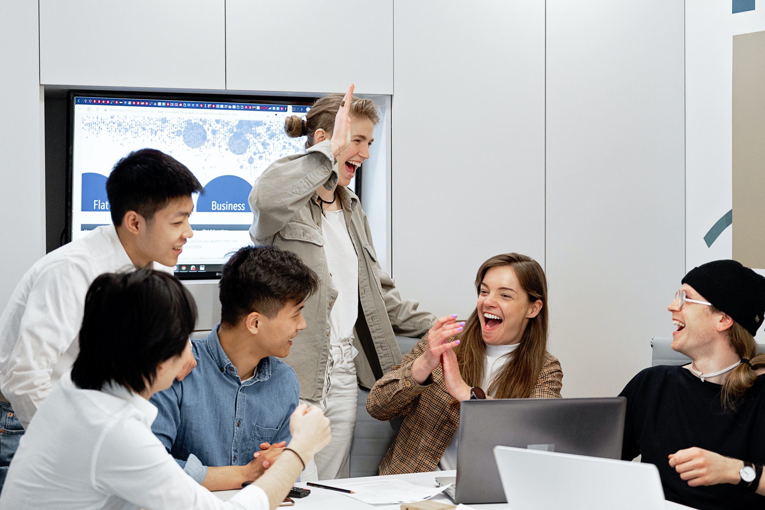 A group of young employees bantering in a meeting.