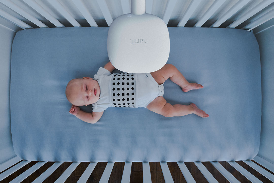 A baby being monitored by a Nanit Pro Camera in his cot.