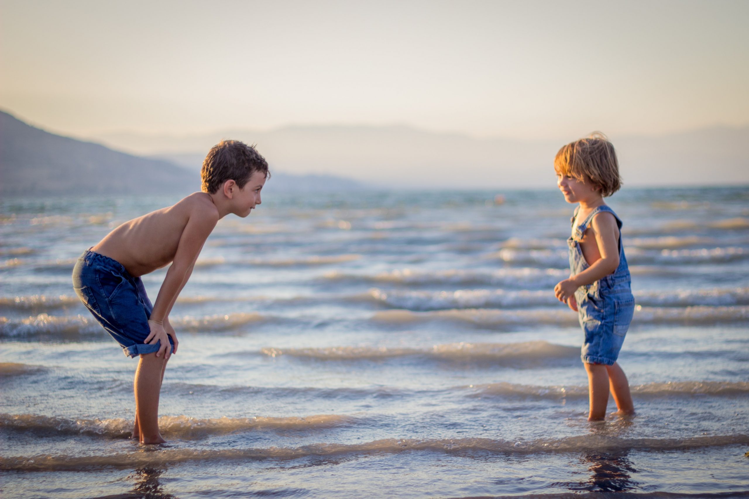 Two young boys playing on a Cornwall beach, the sea lapping at their feet.