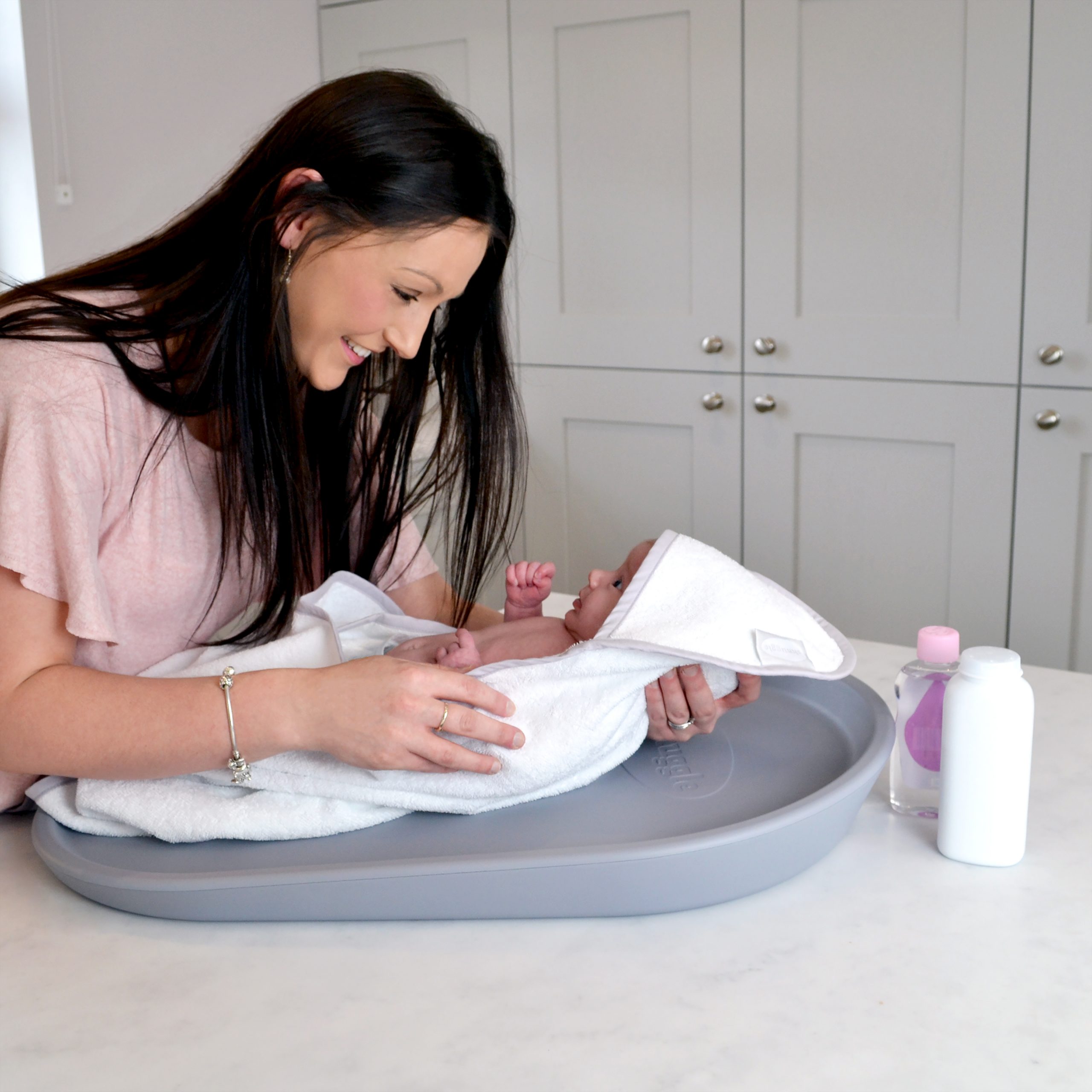 A woman changing her baby's nappy with a Shnuggle Squishy Changing Mat.