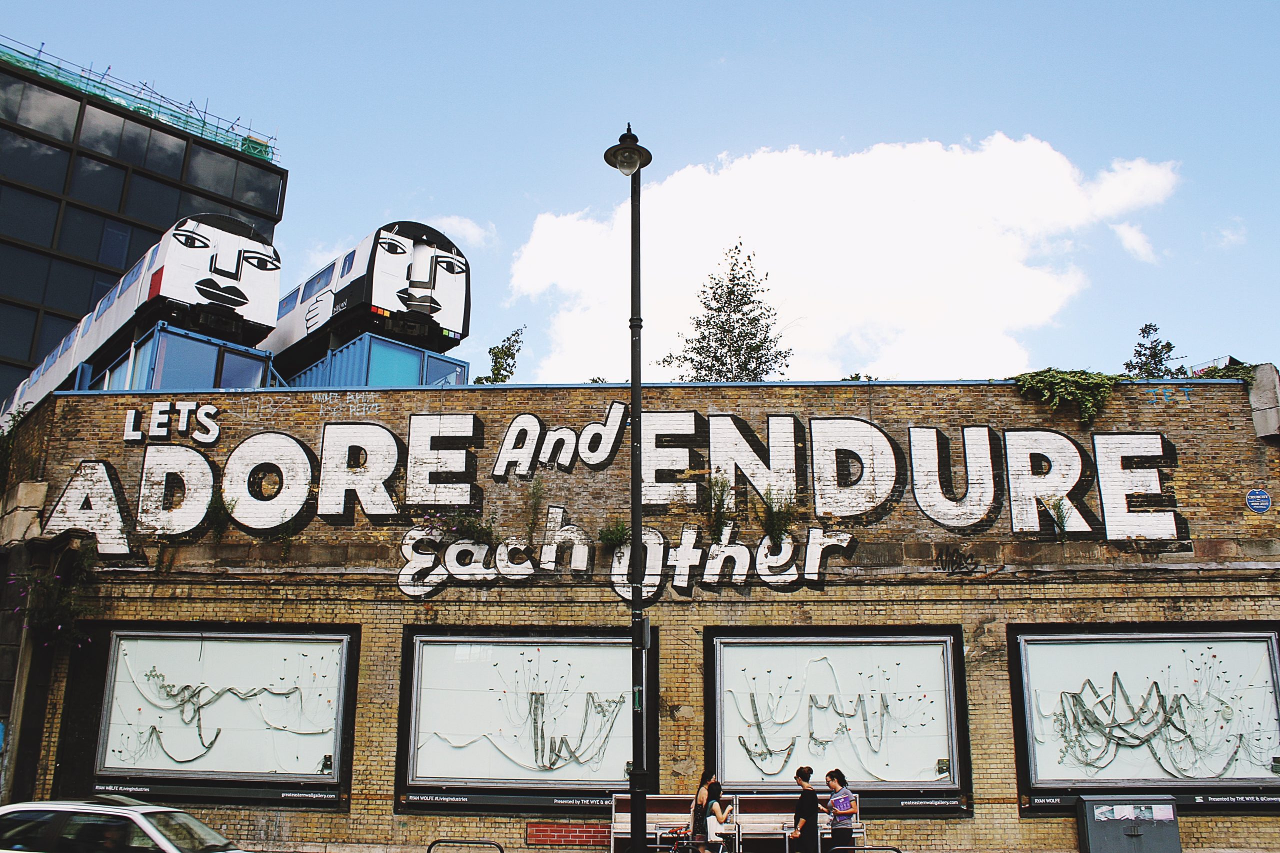 A wall of street art in Shoreditch, London, underneath two parked trains.