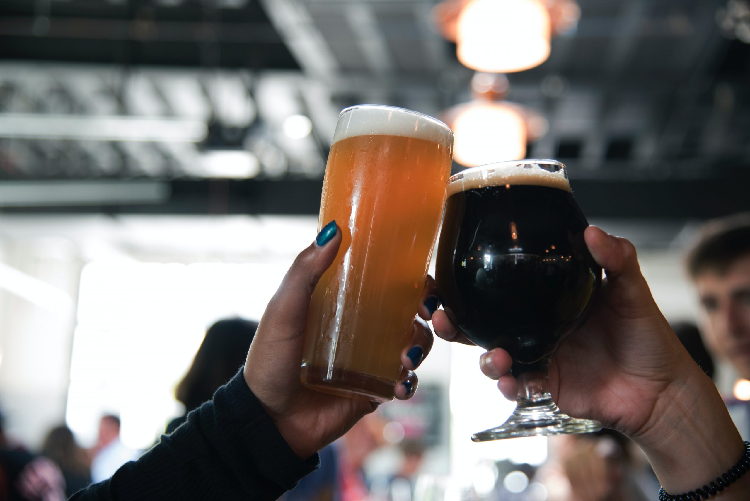 Two alcohol-free beers being toasted in a busy pub.