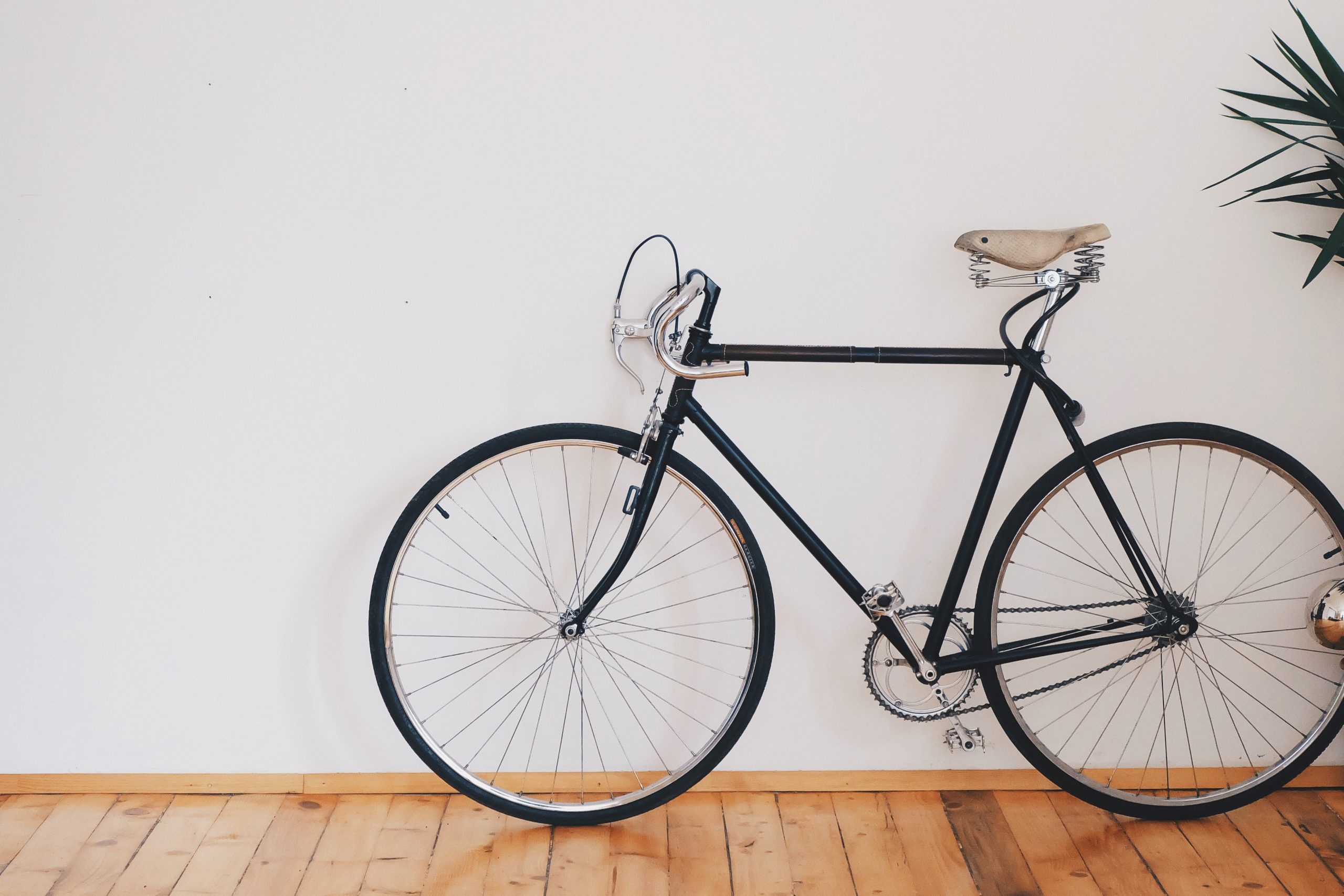 A bicycle leaning against a white wall of a room.