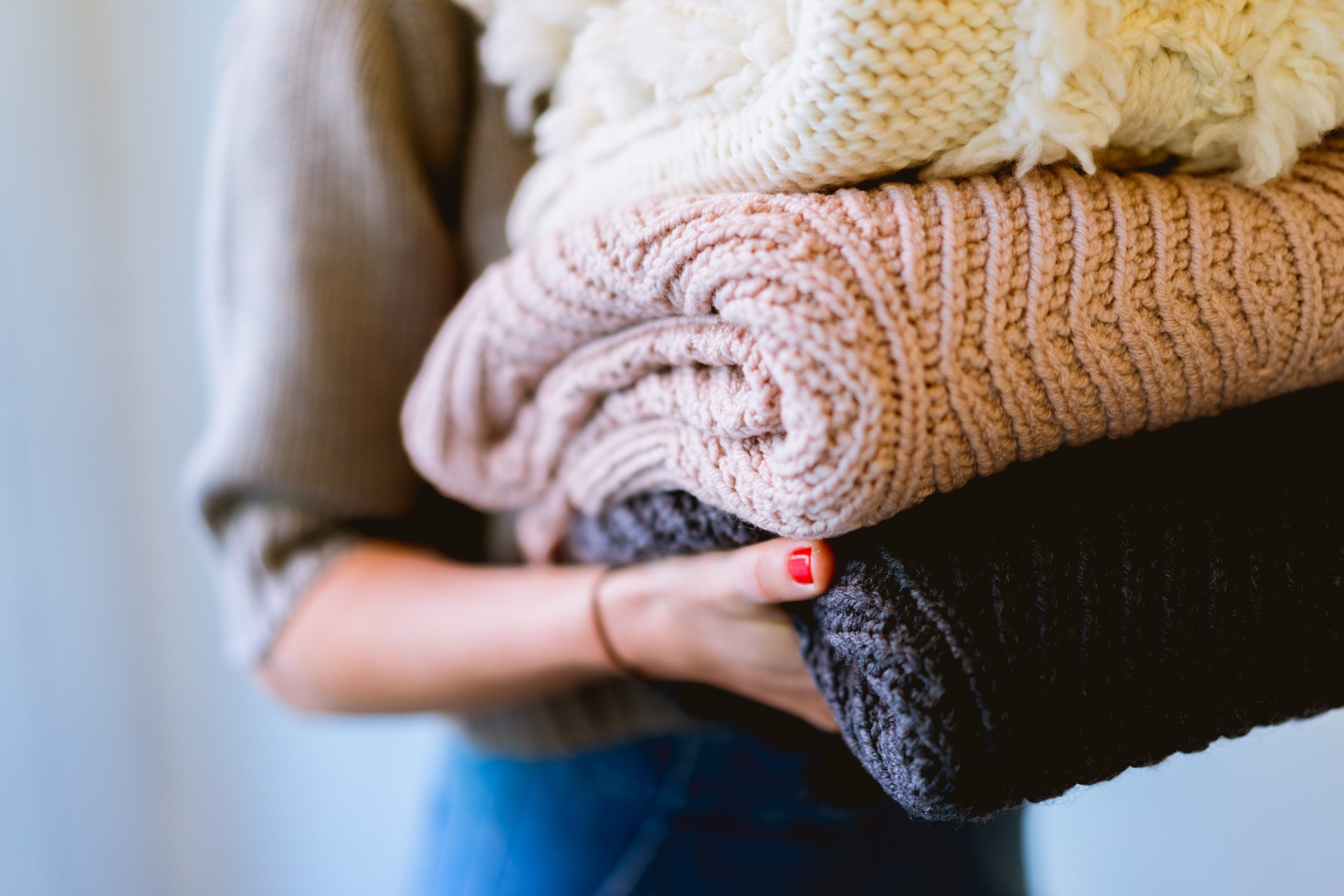 A woman carrying a stack of clothes to be washed.