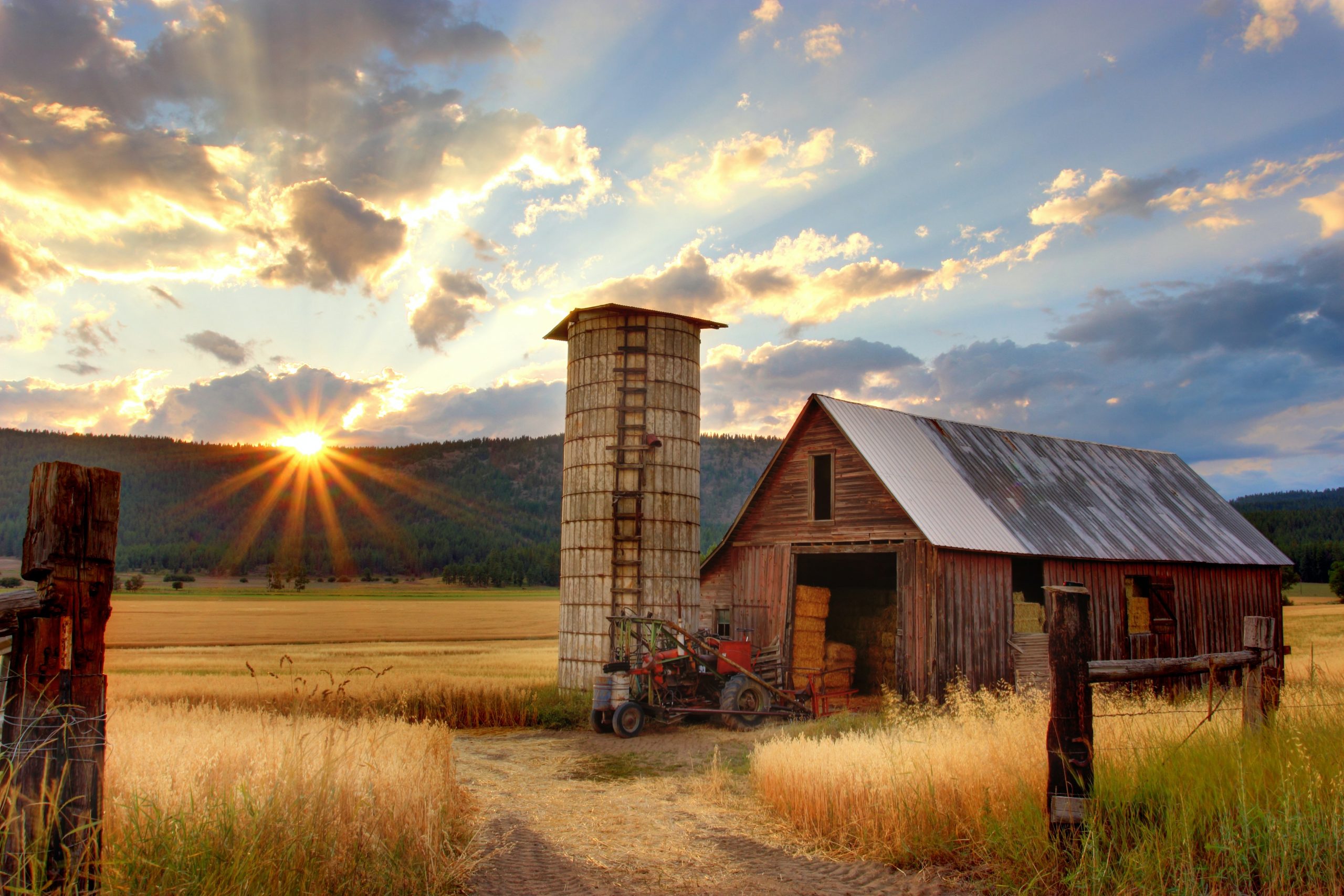 The sun setting on an old barn in the countryside.