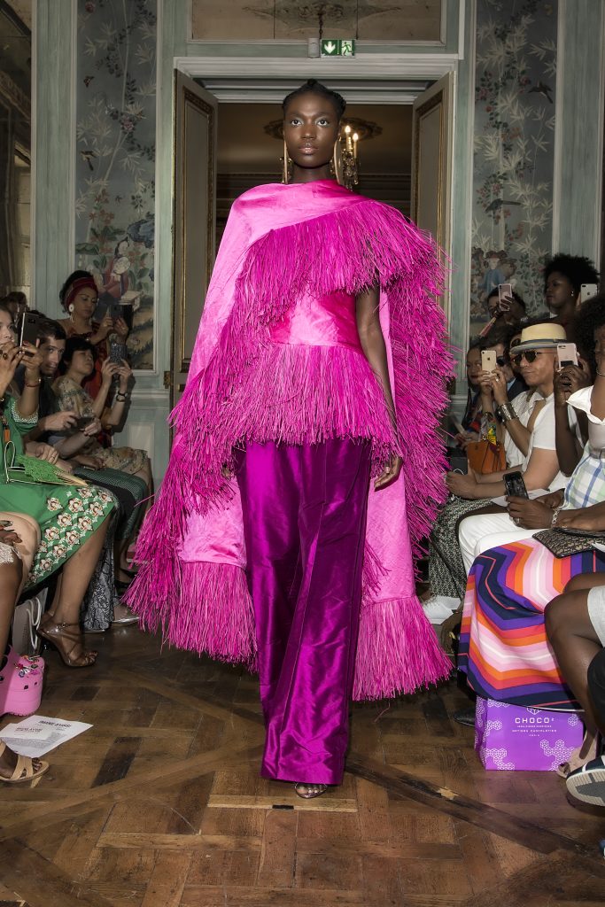 African model in bright fuchsia attire on a catwalk at a fashion show