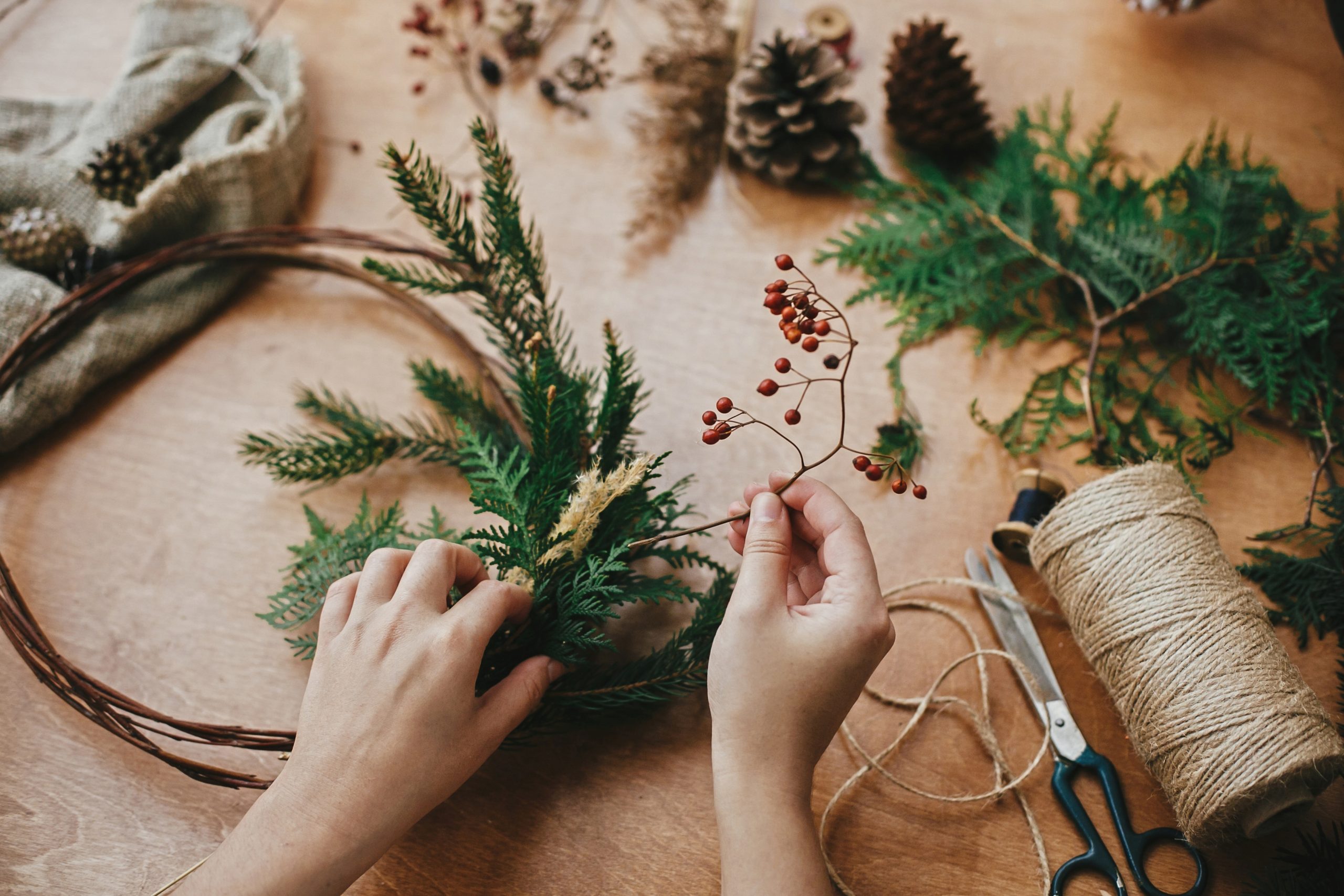 Close-up of a pair of hands making a Christmas garland.